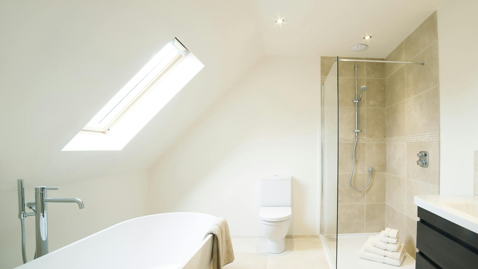 Bad mit Dachschräge, darunter eine Badewanne direkt am Fenster.