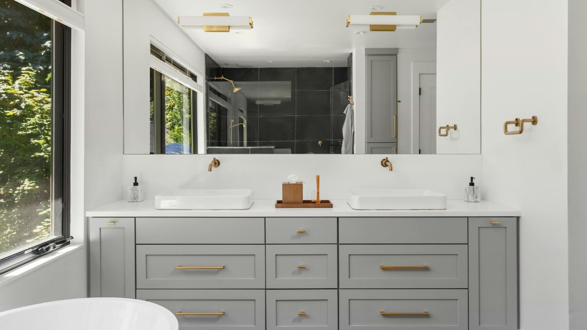 Koupelnová stěna se vsazeným šedým zrcadlem a skříňkou pod umyvadly.