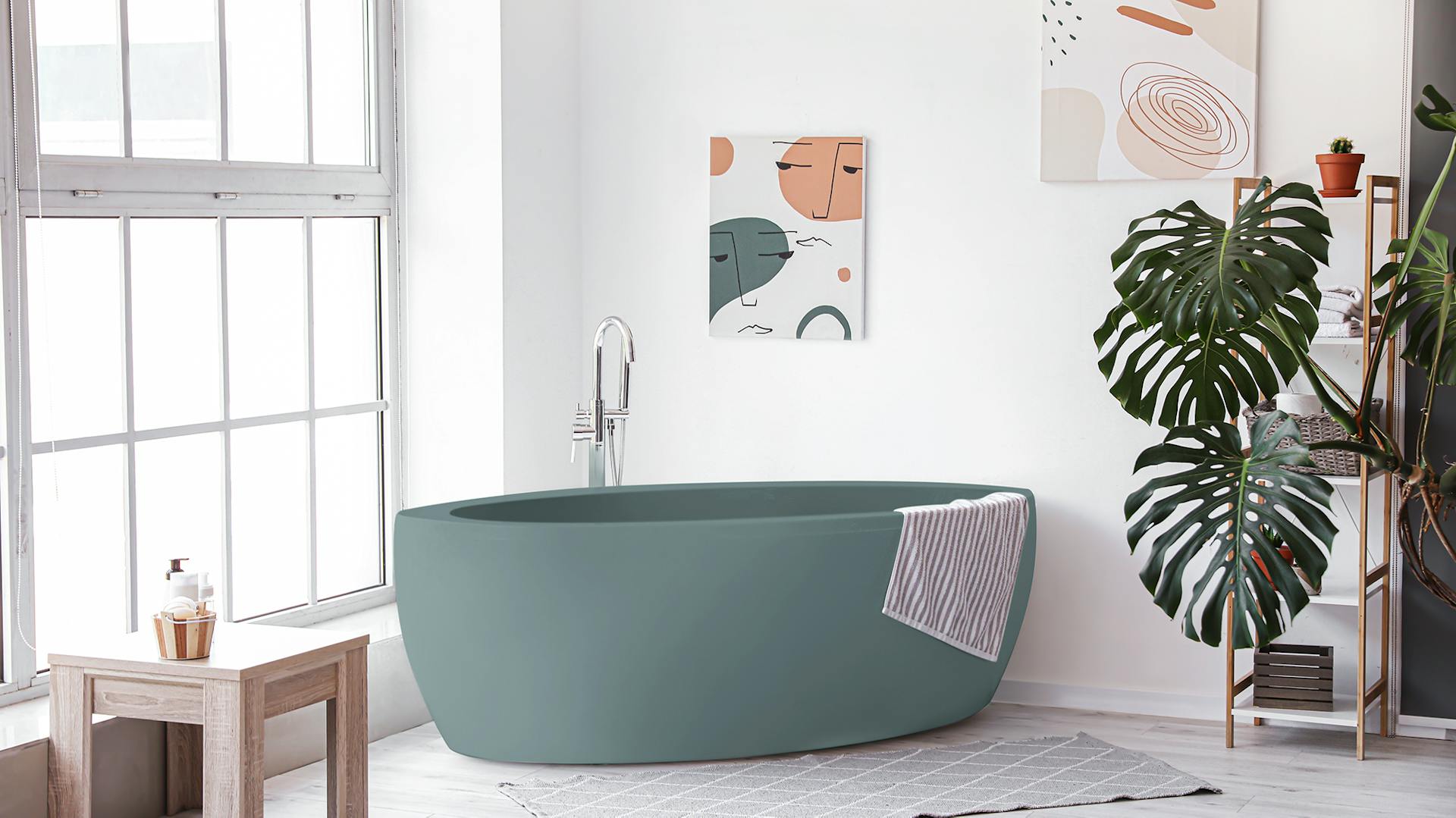 Tyrkysová volně stojící vana mezi velkým oknem a dekorativním regálem s rostlinami.