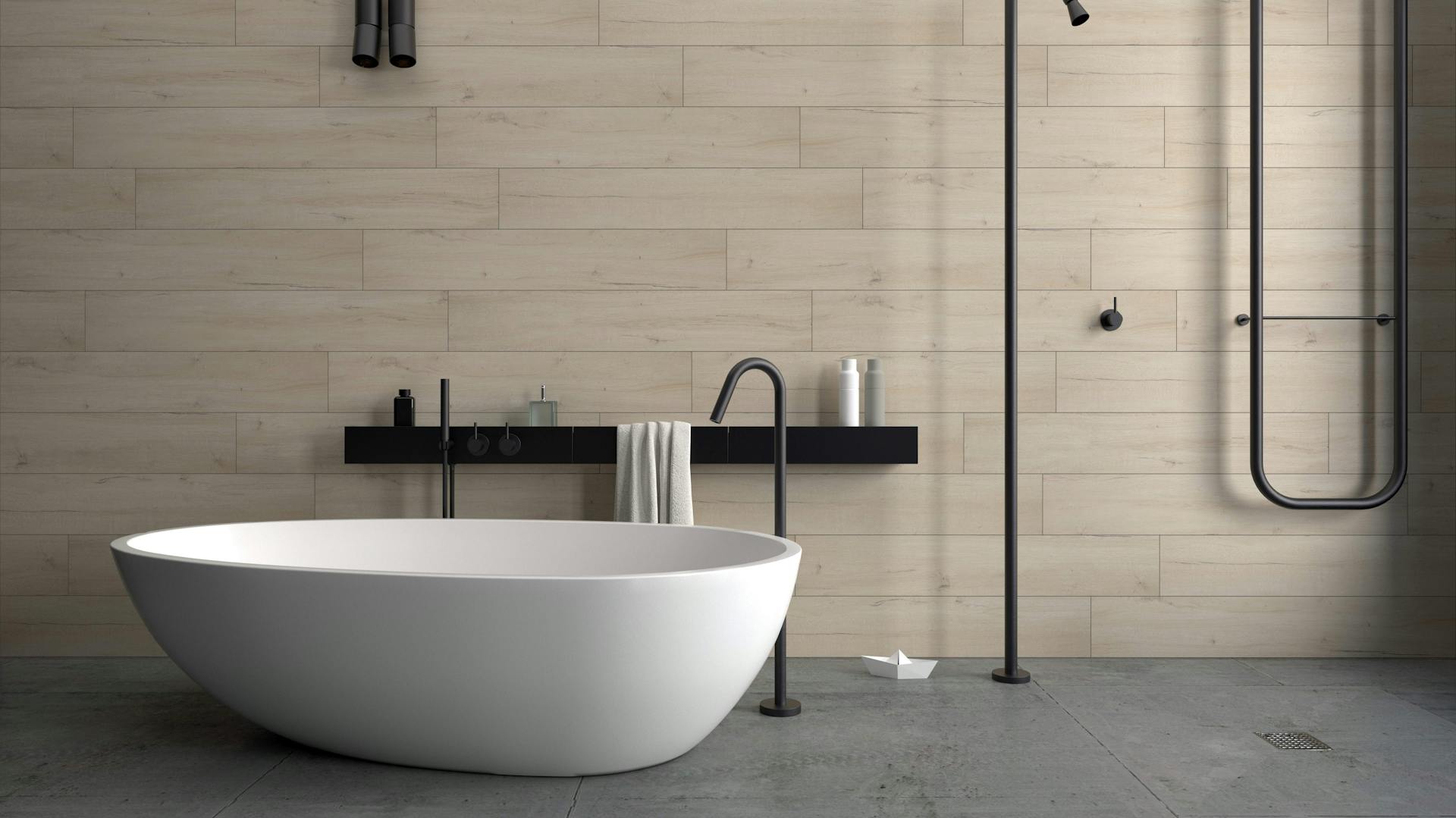 Beton-Bad mit mattschwarzen Armaturen und einer freistehenden Badewanne.