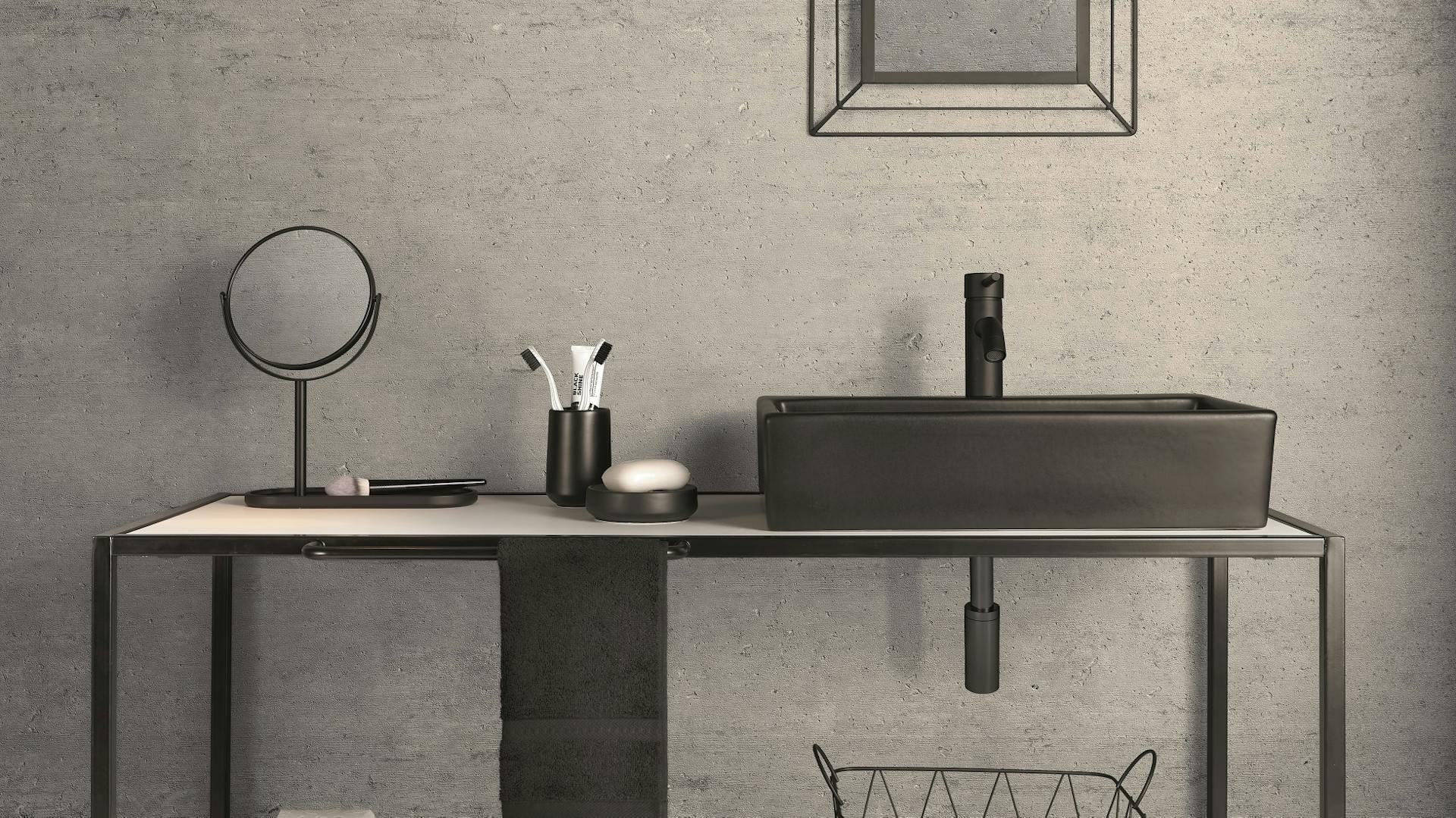 Beton-Bad mit Regal und schwarzen Dekoelementen.