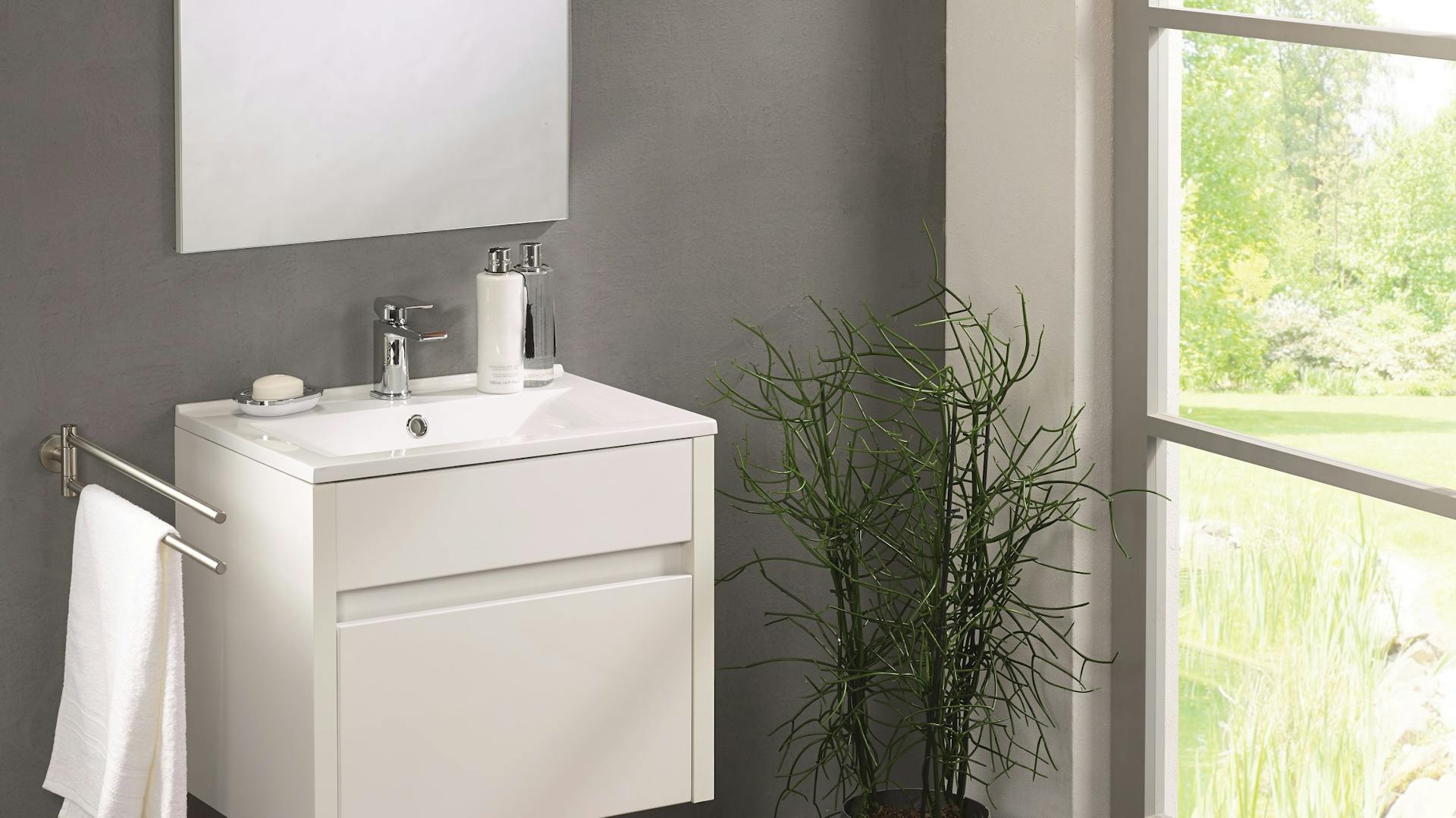 Beton-Bad im wohnlichen Stil mit Waschtisch, Pflanze und natürlichen Akzenten.