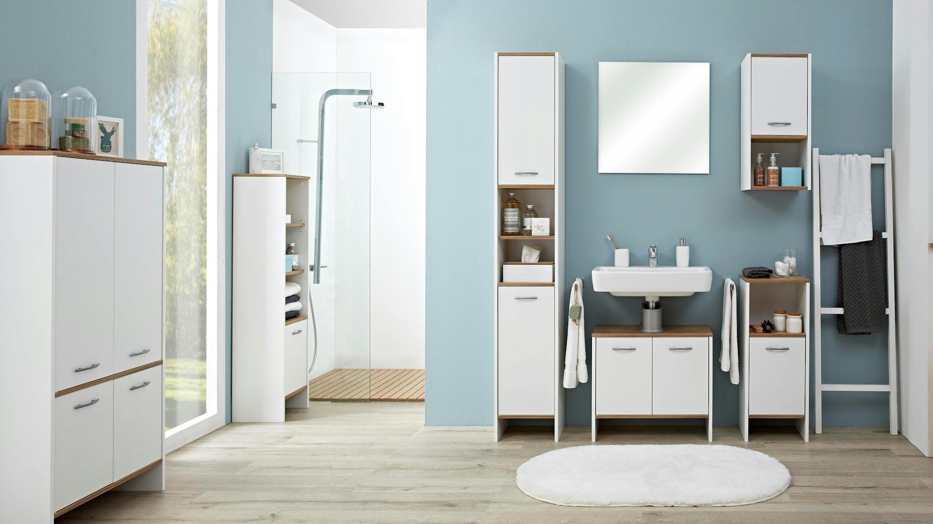 Fugenloses Bad mit weißen Möbeln und Boden in Holzoptik.