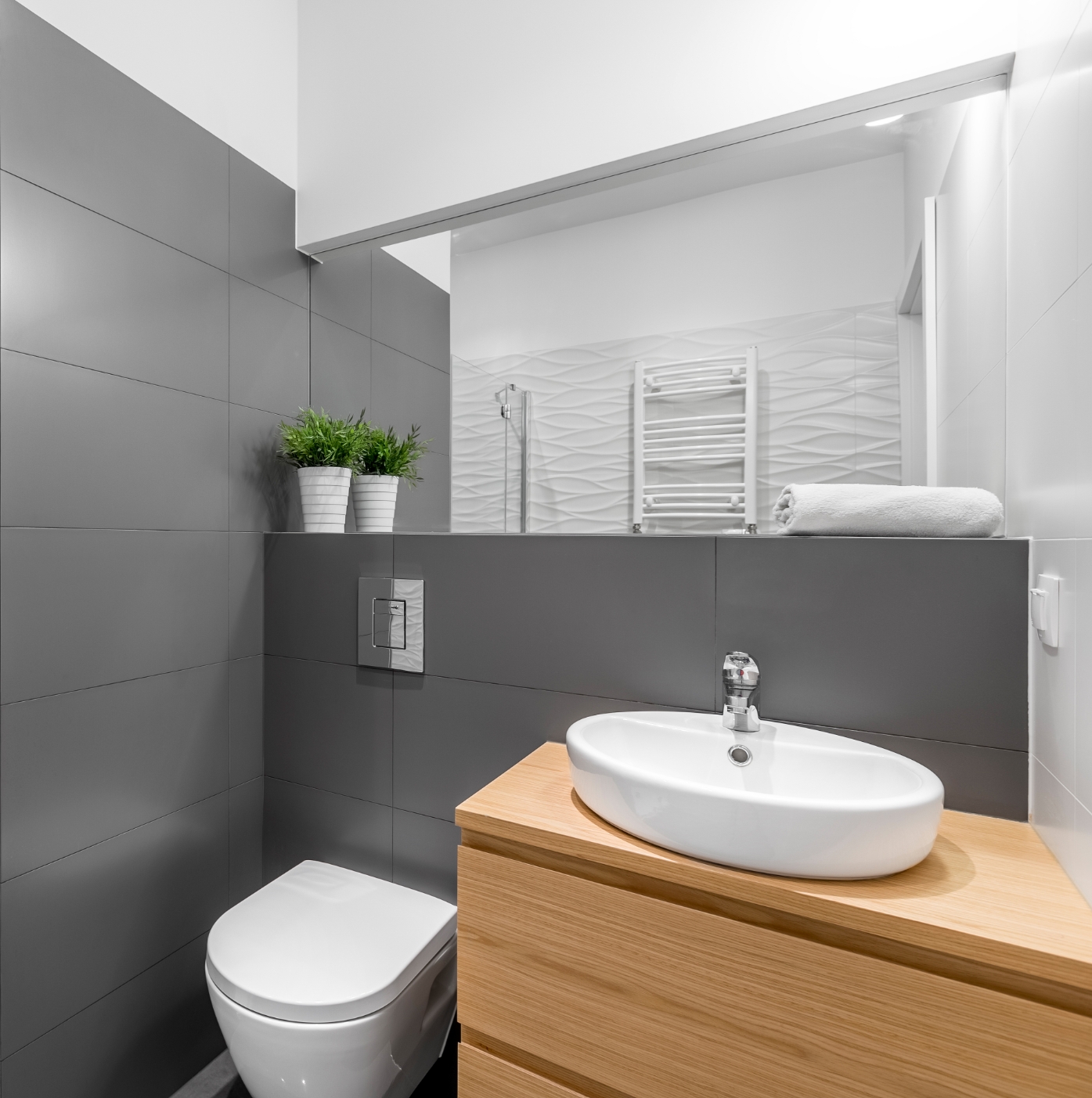 Piccolo bagno grigio-bianco con sanitario, lavabo in legno e specchio