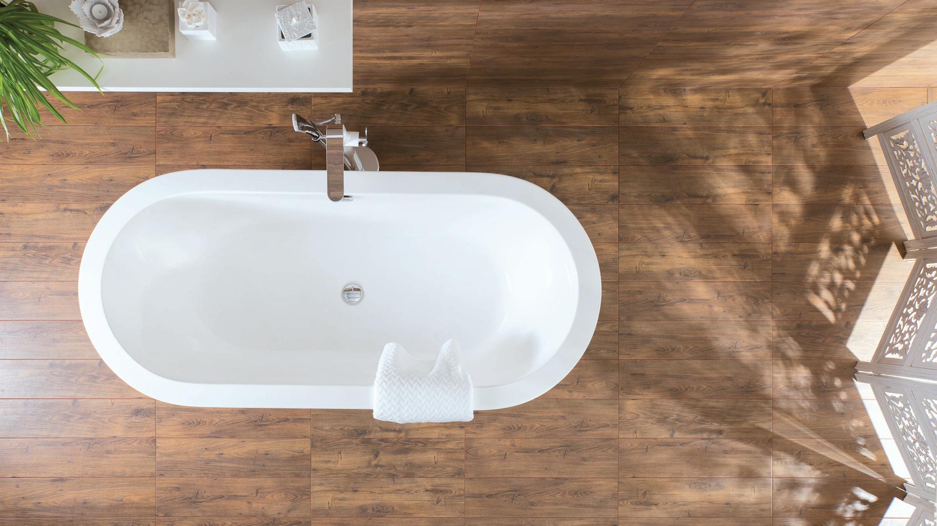 Natürliches Bad mit Fliesen in Holzoptik und einer freistehenden Badewanne.