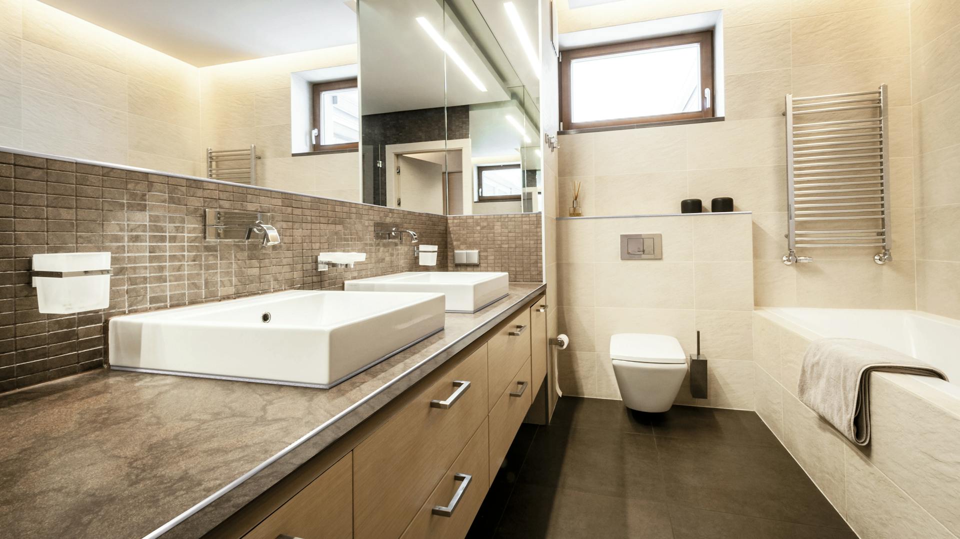 Schlauchbad mit Fliesen, Badewanne und großer Spiegelfront.