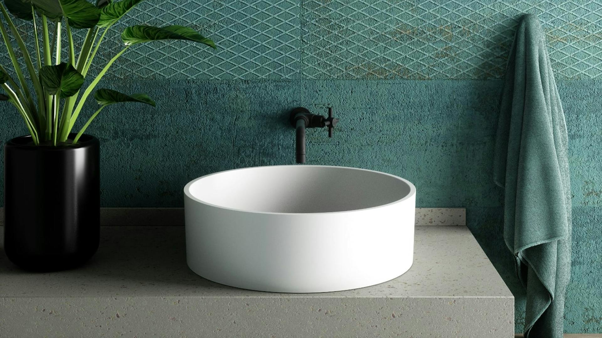 Weißes Waschbecken vor einer Wand mit bläulich grüner Farbe.