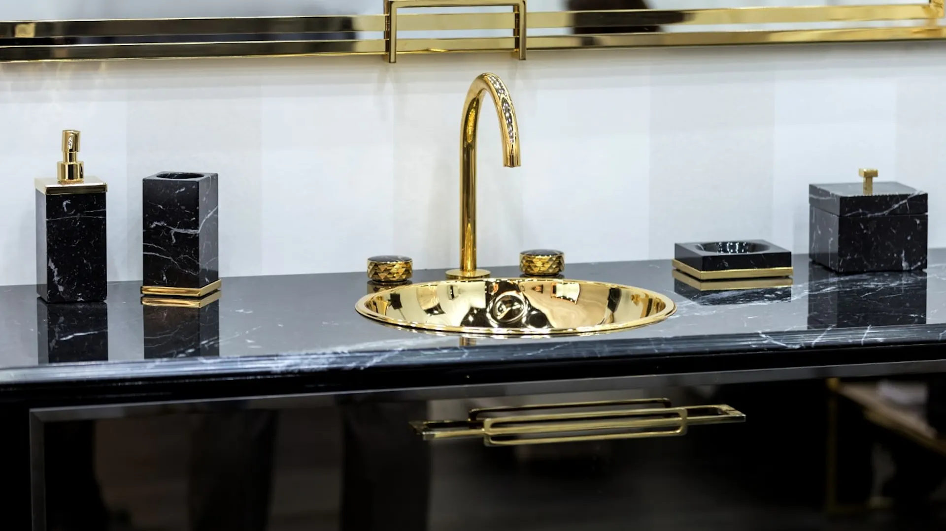 Goldenes Waschbecken auf schwarzem Unterschrank.