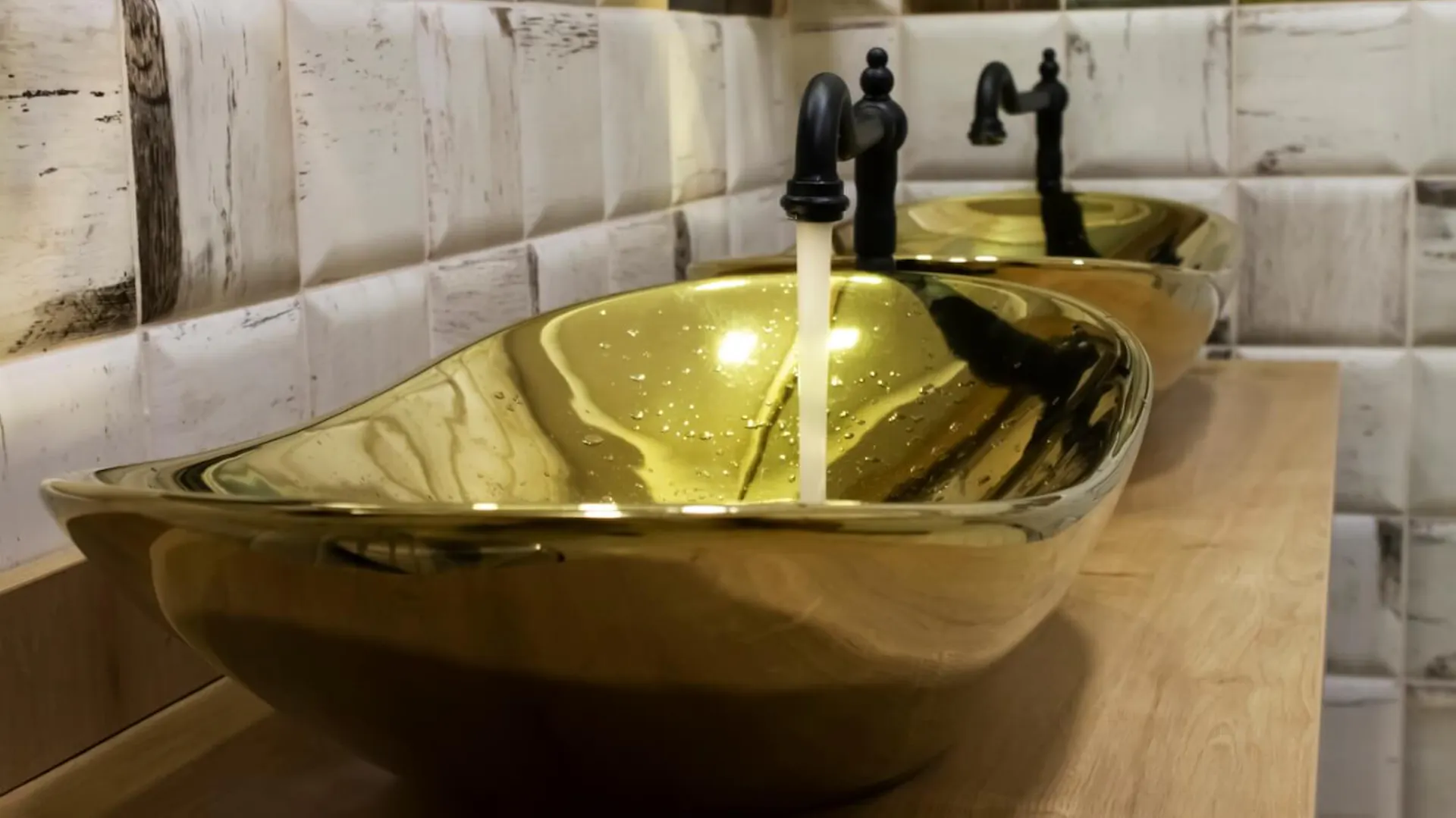 Goldenes Waschbecken mit schwarzem Wasserhahn.