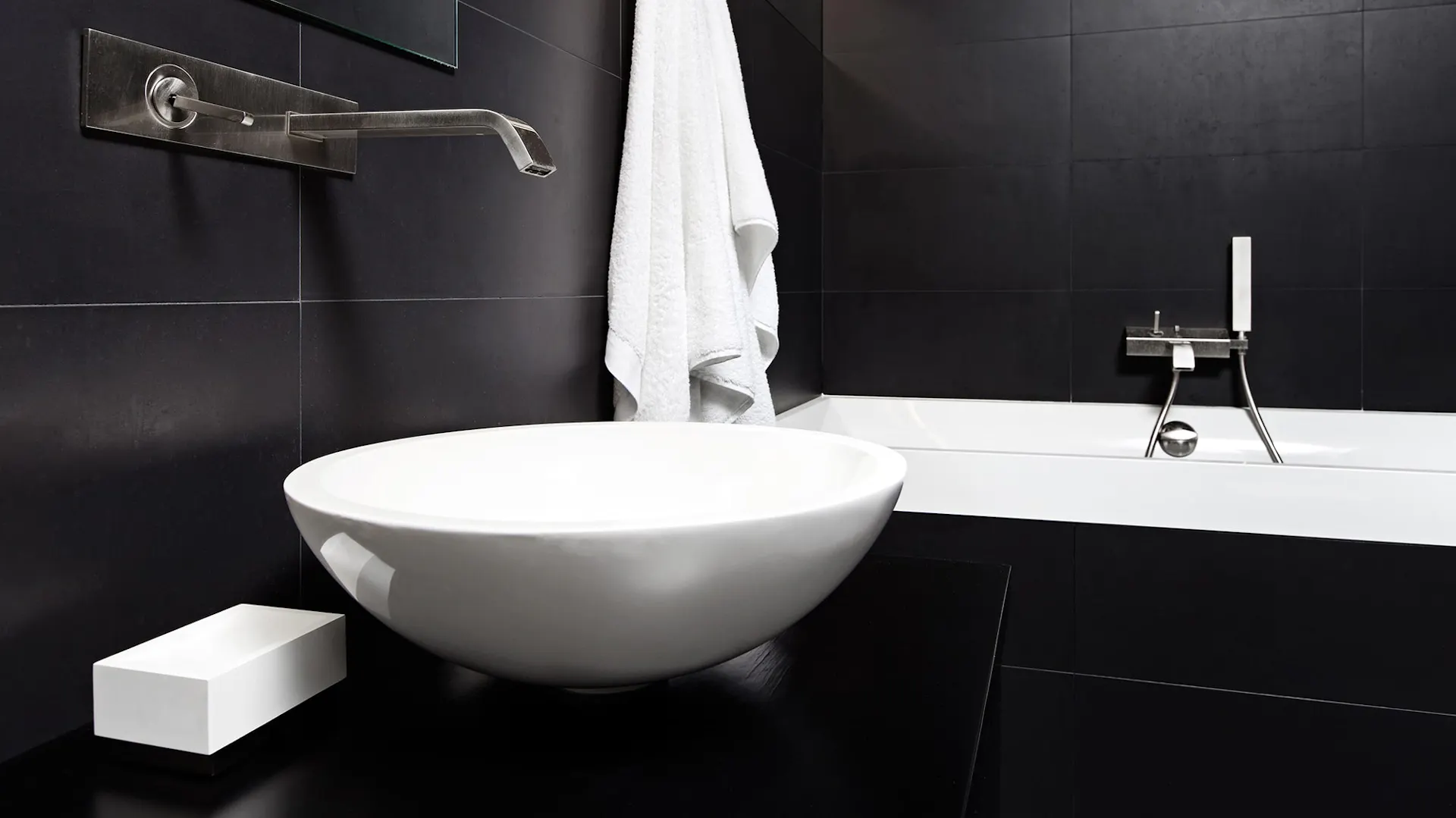 Schwarzes Badezimmer mit weißen Armaturen.