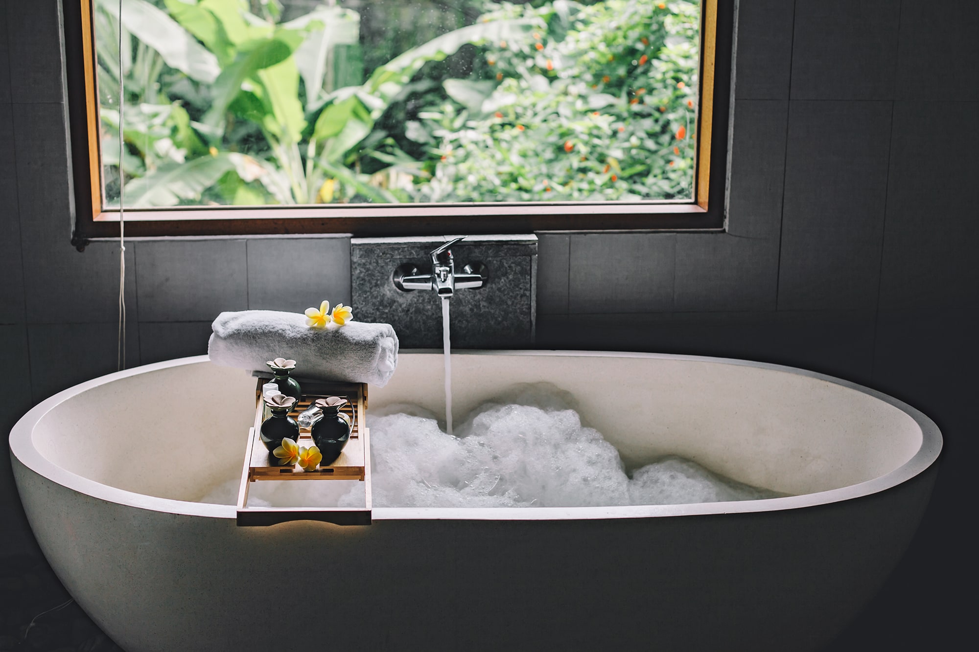 Weiße Badewanne in dunklem Bad.