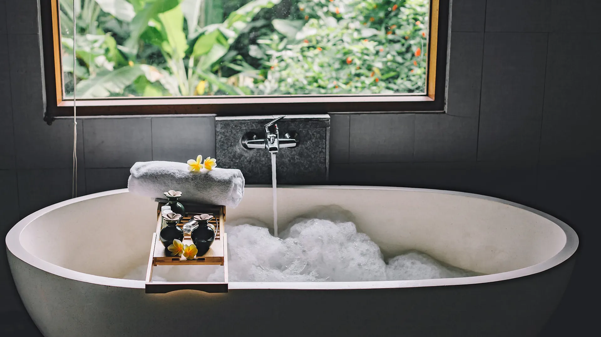 Weiße Badewanne in dunklem Bad.