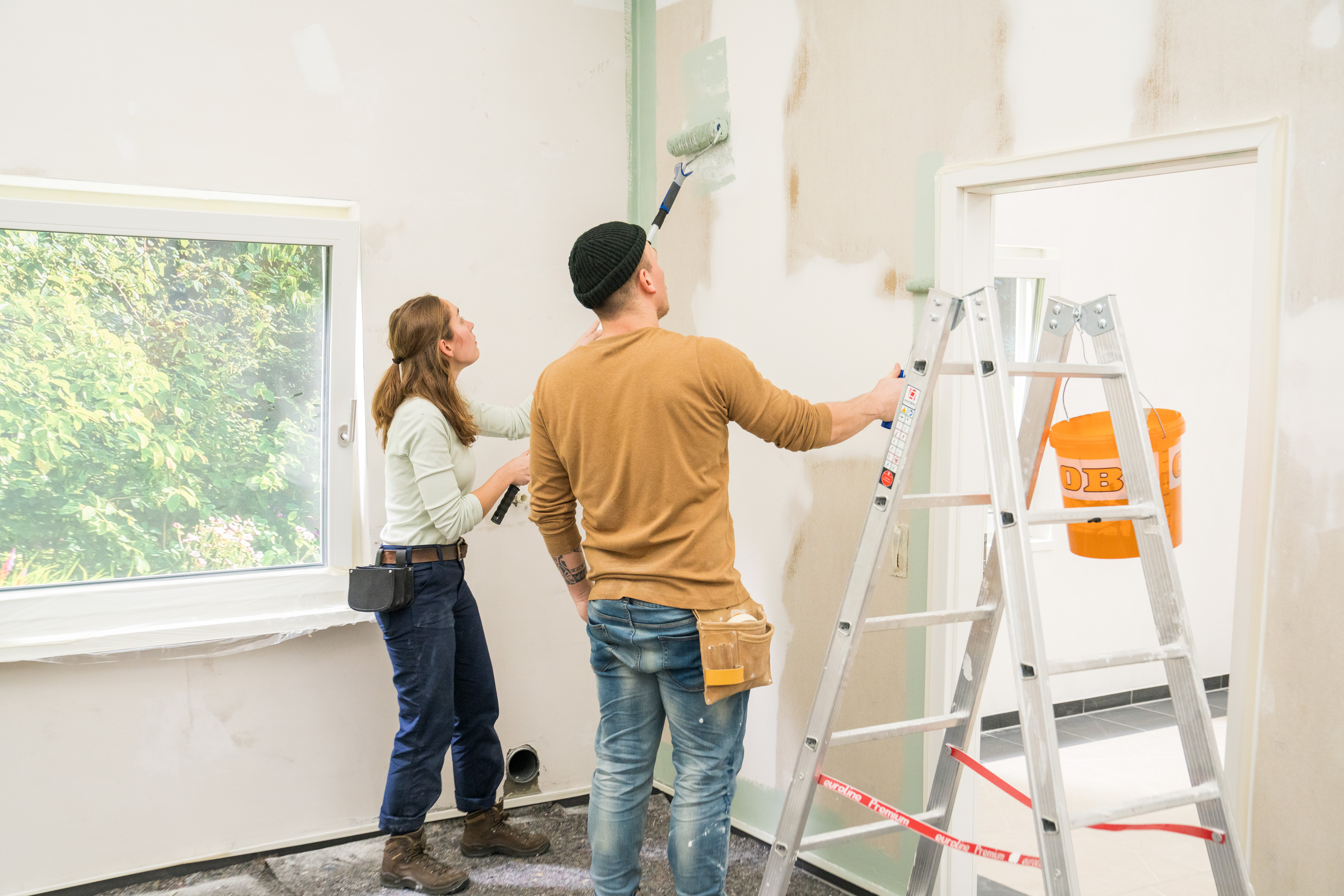 Degli artigiani dipingono la parete con dei grandi rulli.