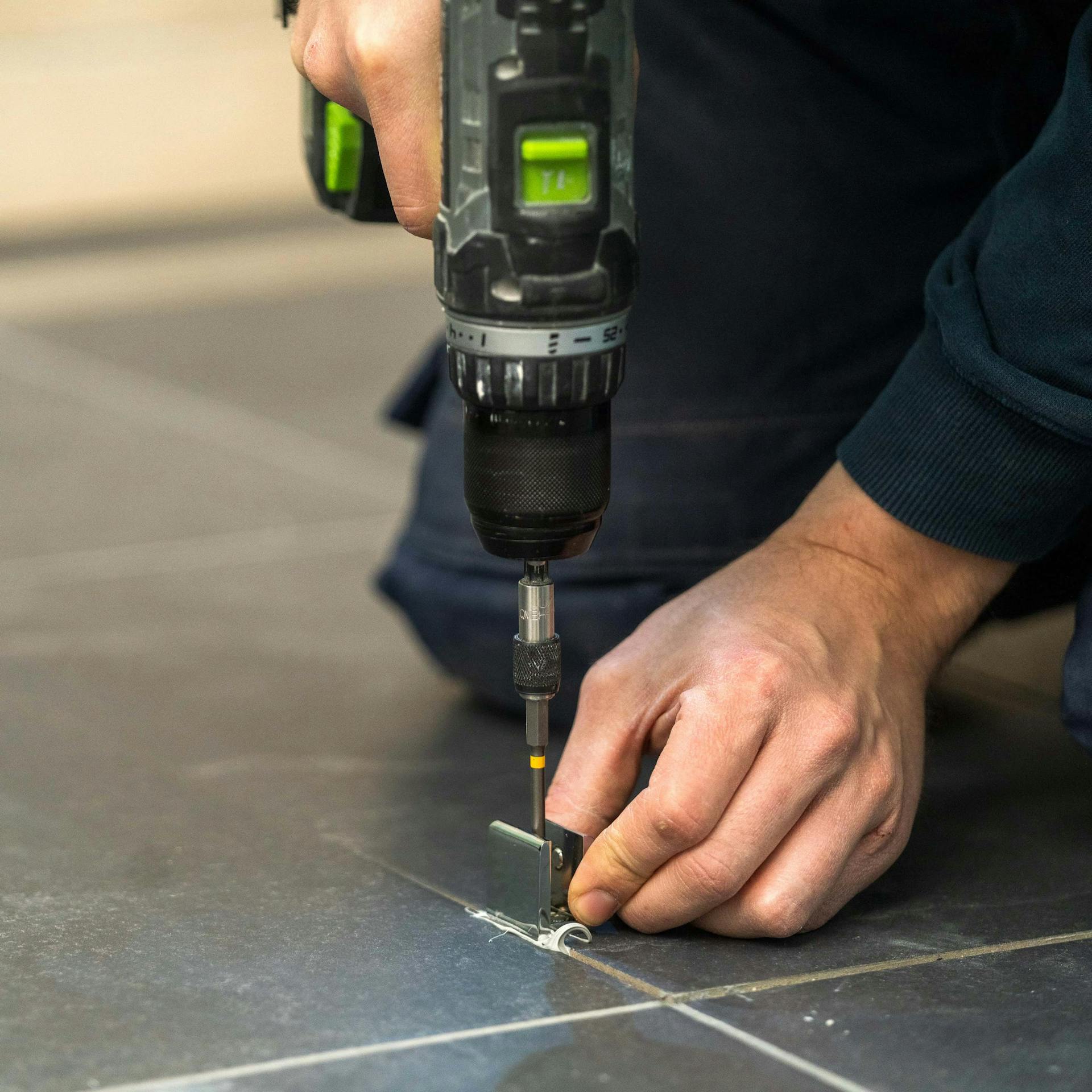 Valaki padlótartót szerel fel egy üveg zuhanyfalhoz.