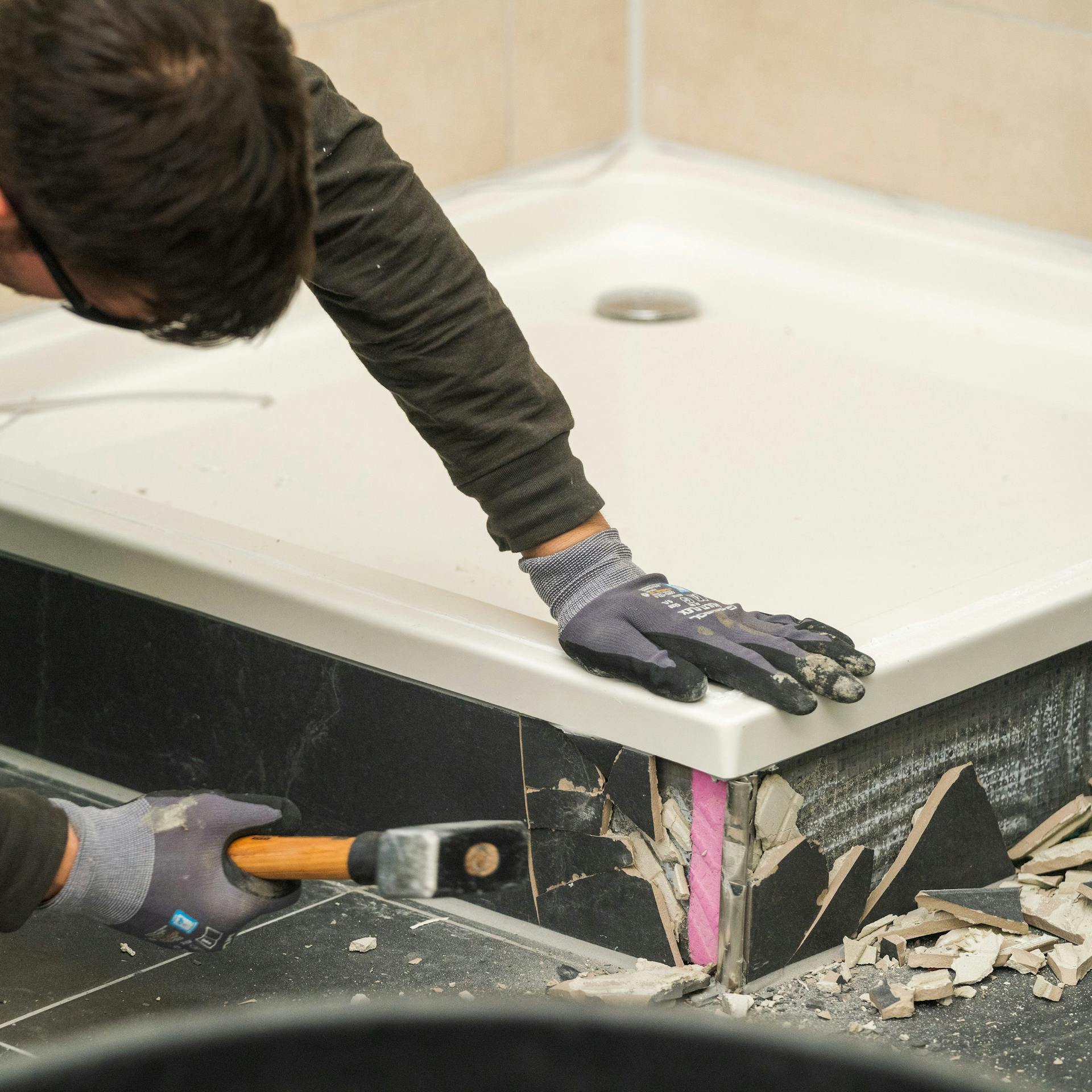 A barkácsoló eltávolítja a régi zuhanyzó csempéjét.