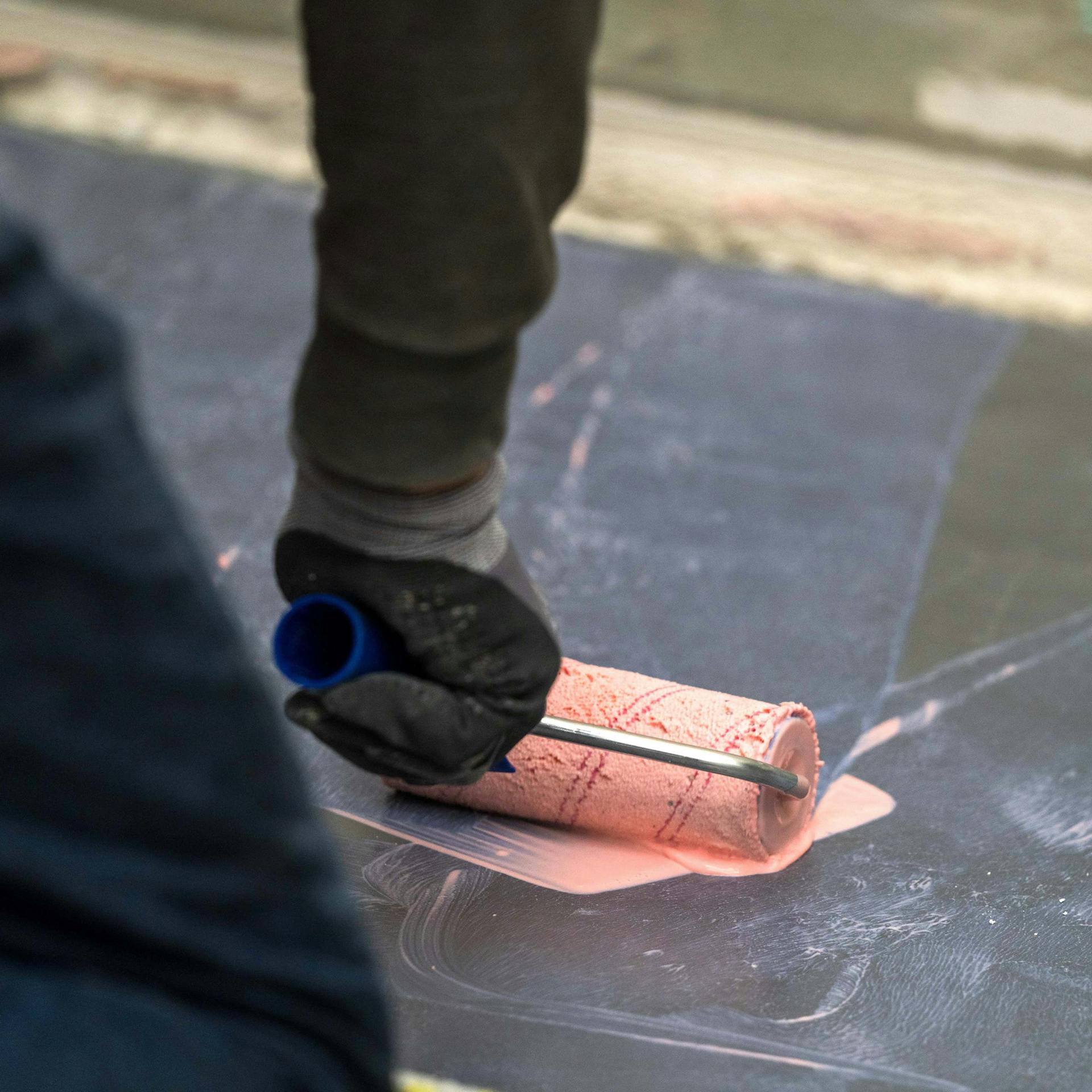 Valaki speciális alapozót hord fel egy burkolható zuhanytálcára.