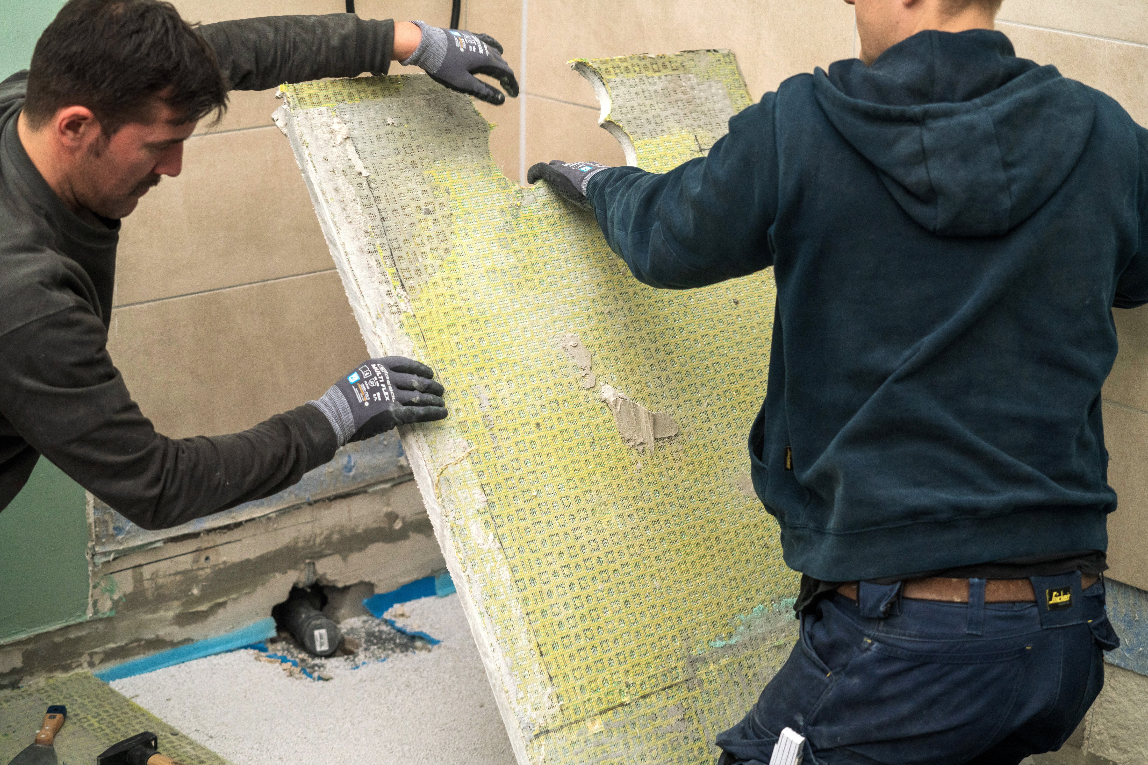 A barkácsolók eltávolítják a zuhanyzó alapját.