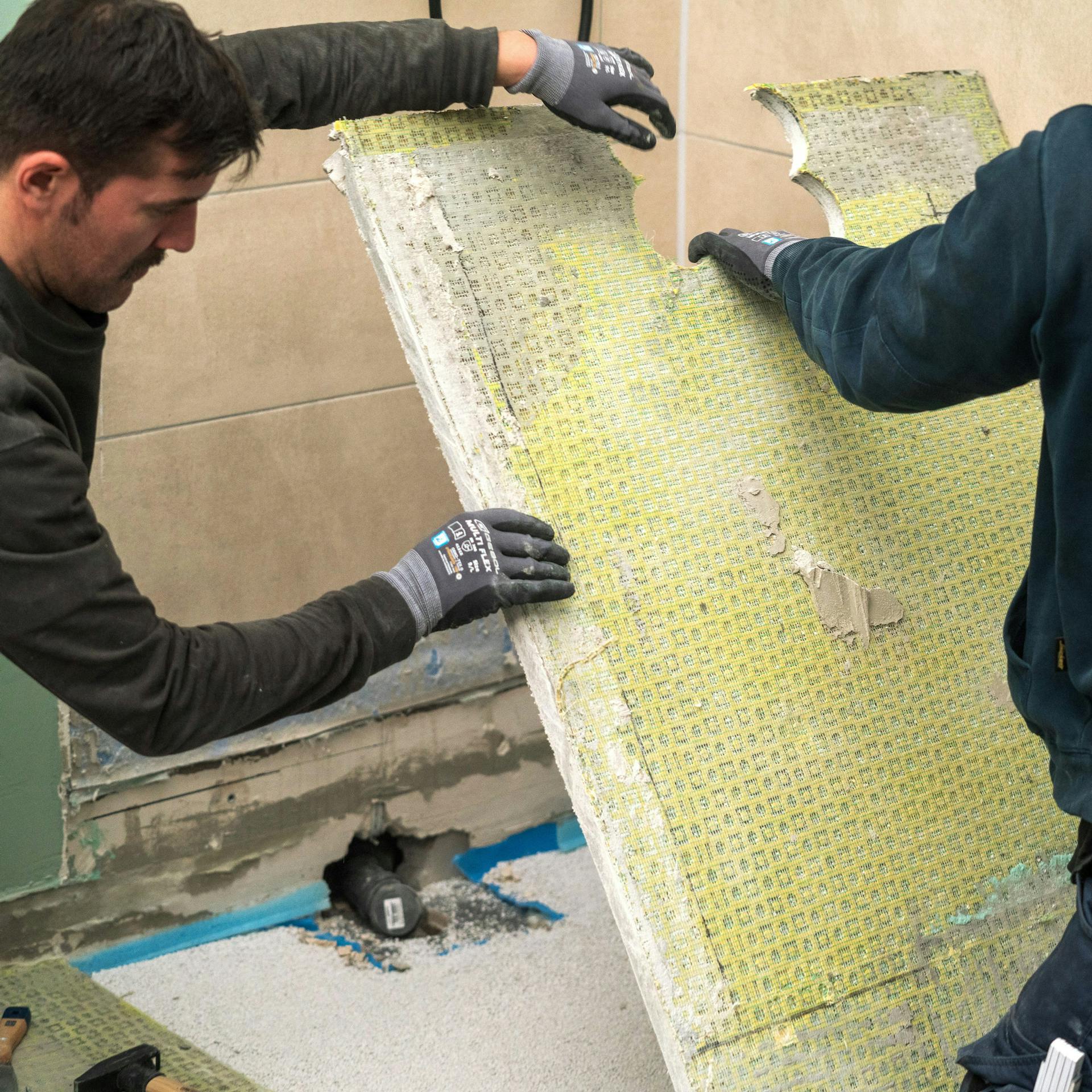 A barkácsolók eltávolítják a zuhanyzó alapját.