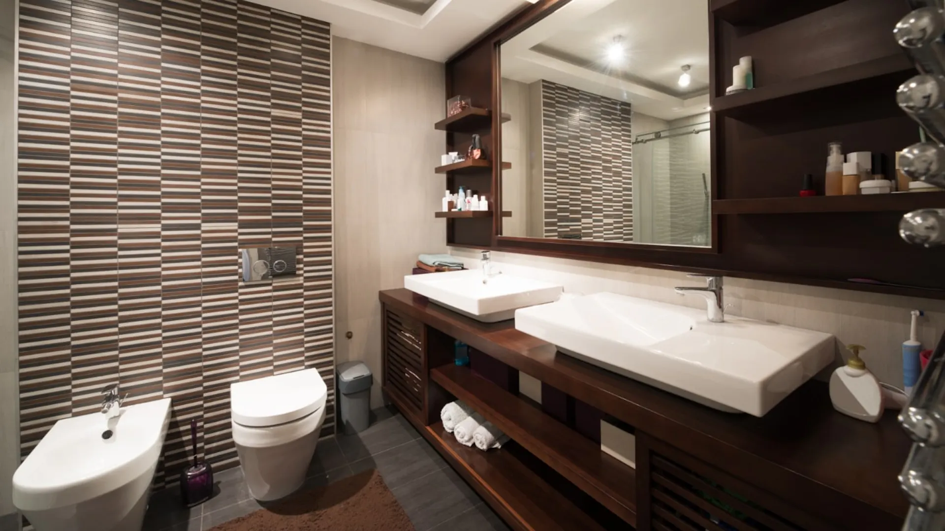 Badezimmer mit dunklen Badmöbeln aus Holz.