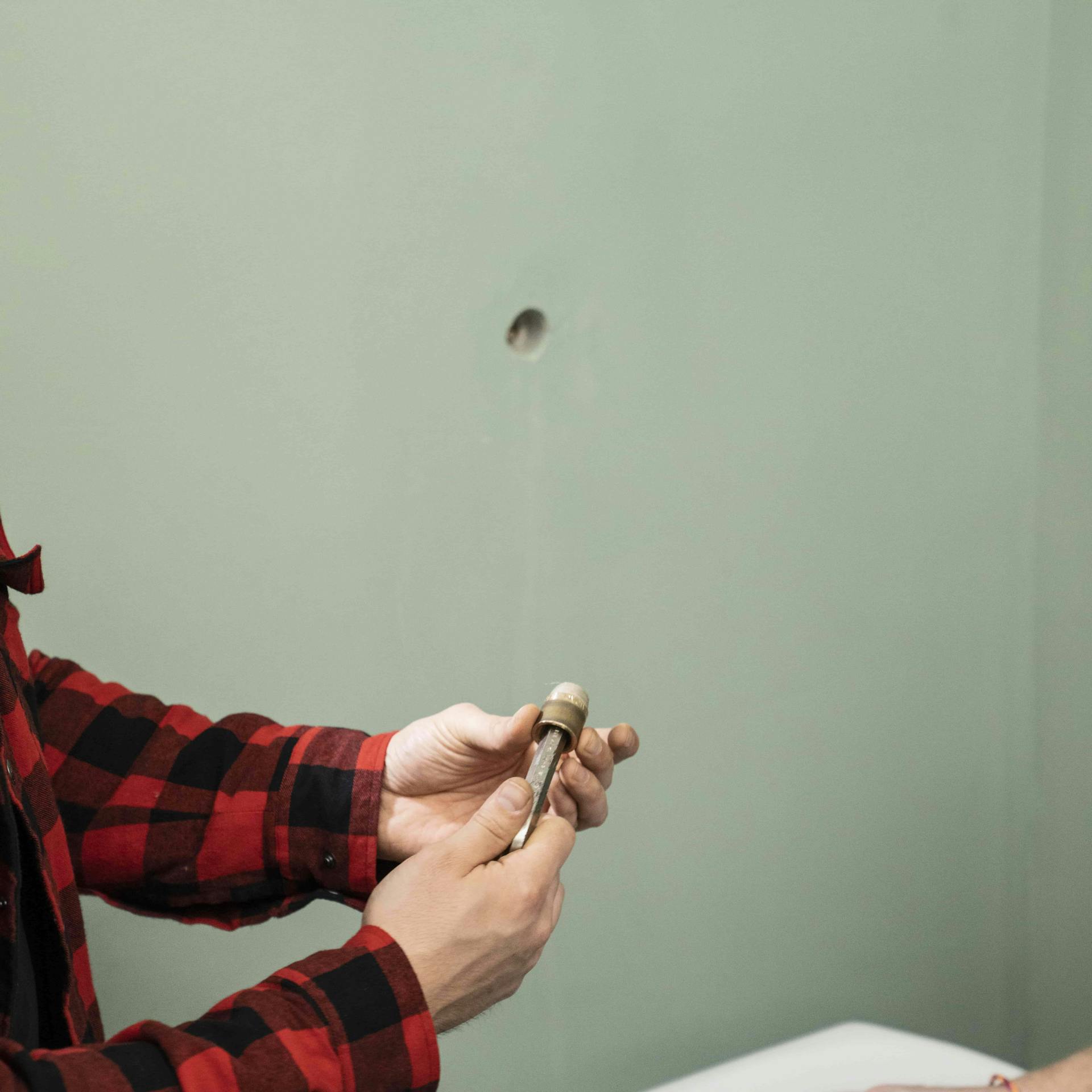 Ein Heimwerker hält ein Eckventil in seiner Hand.