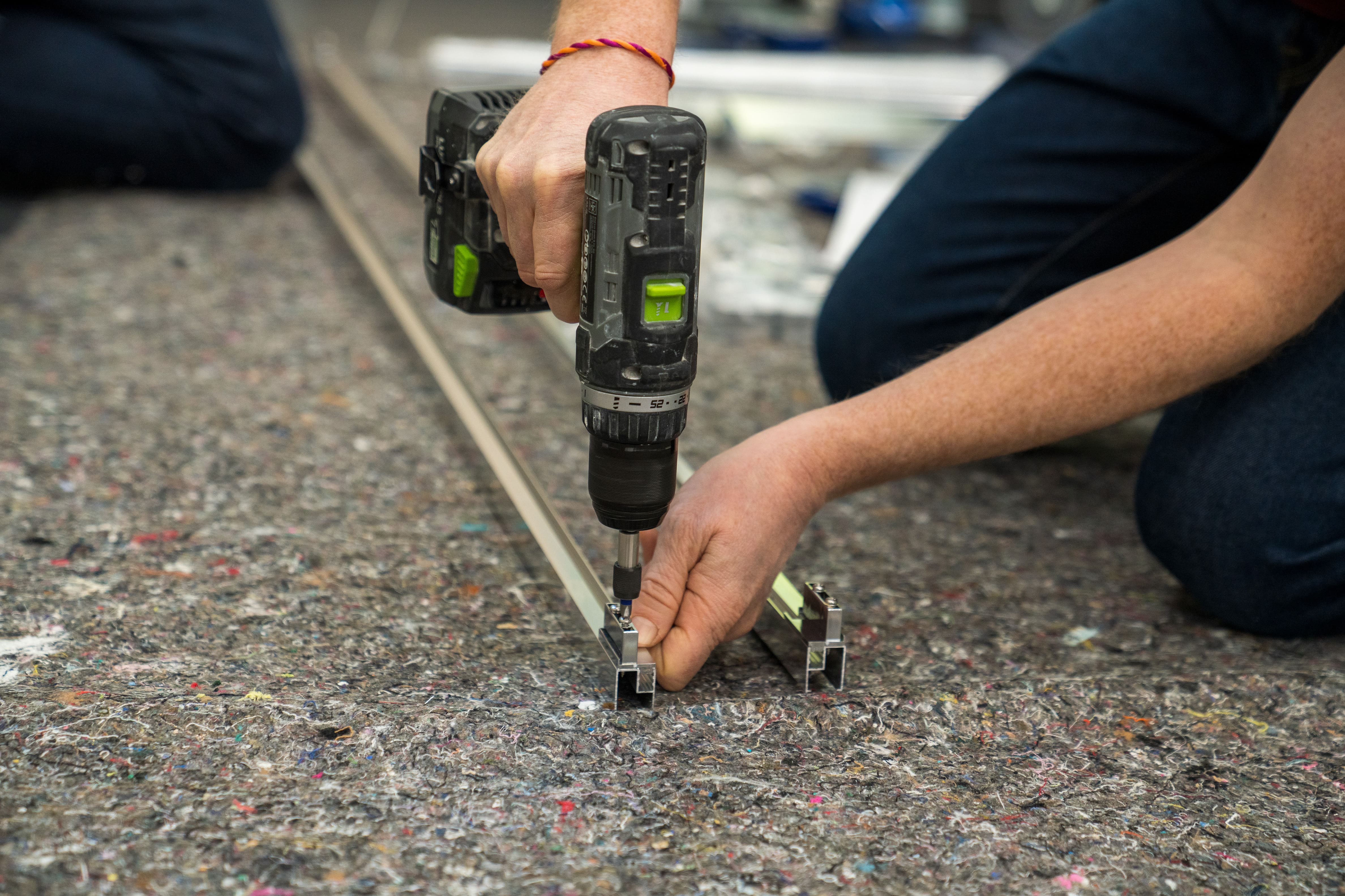 Egy mester akasztókat szerel fel a keret számára.