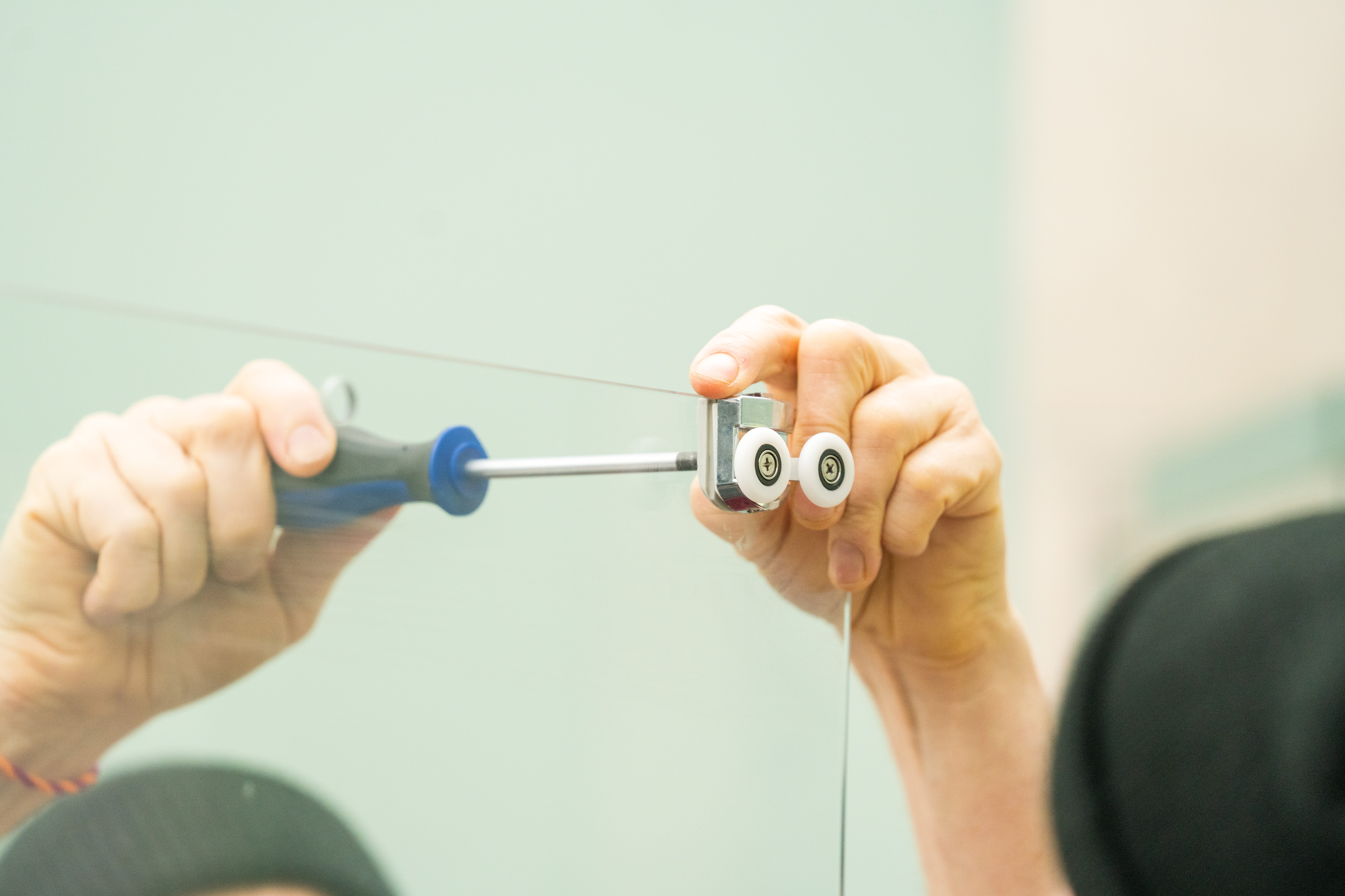 Egy szakember zuhanyajtót szerel be.