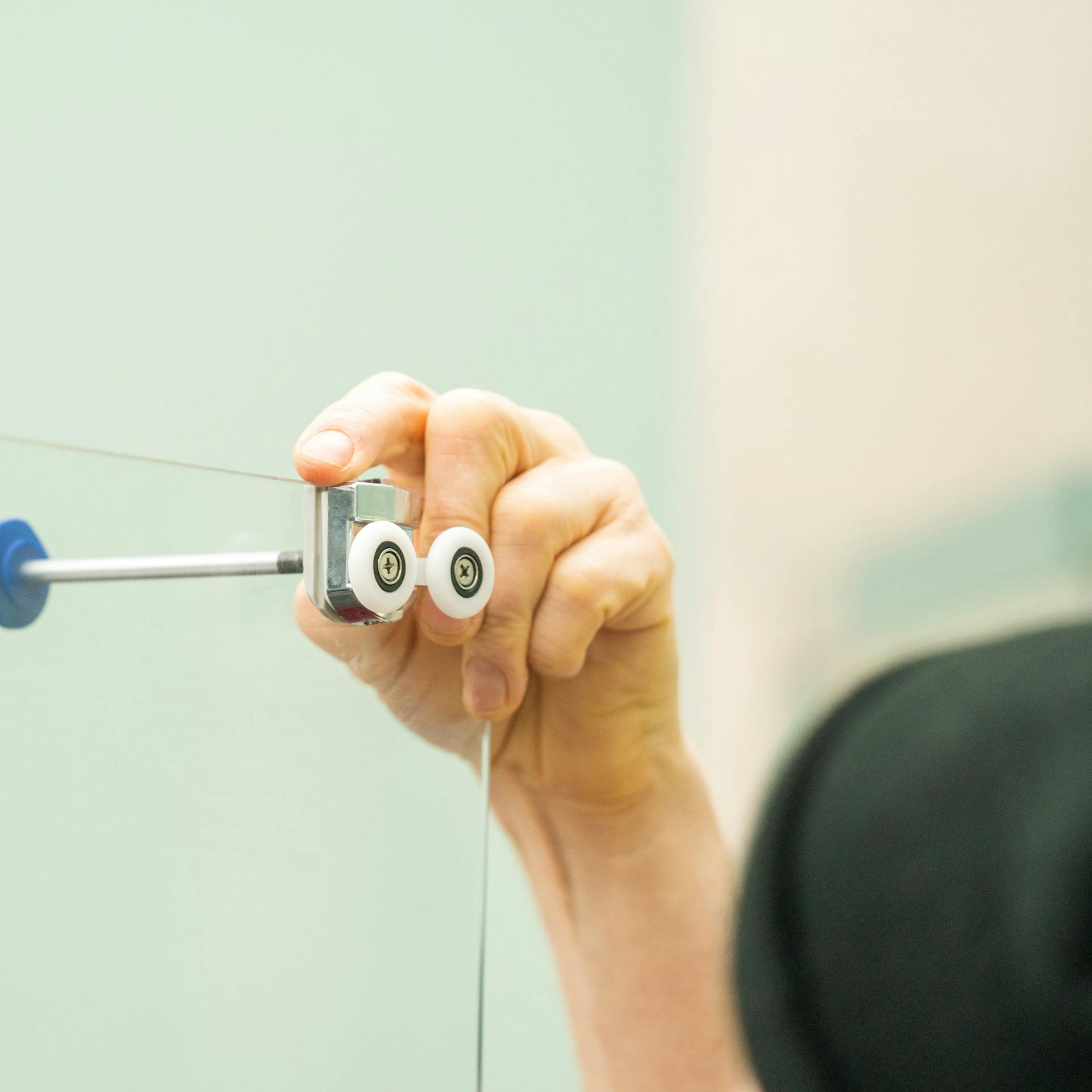 Handwerker baut die Duschtür ein.