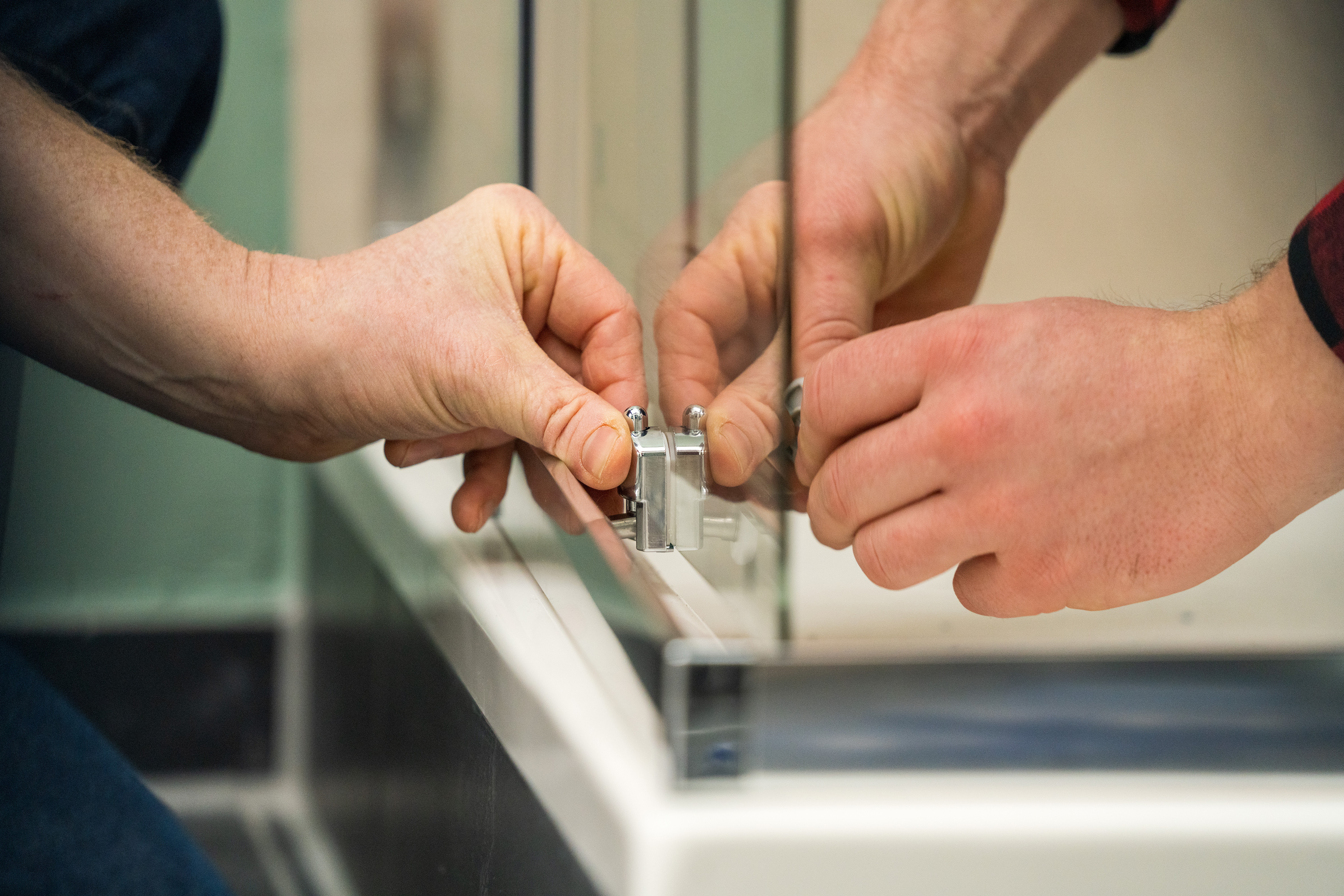 Egy barkácsoló ajtóütközőt szerel fel a zuhanyajtóra.