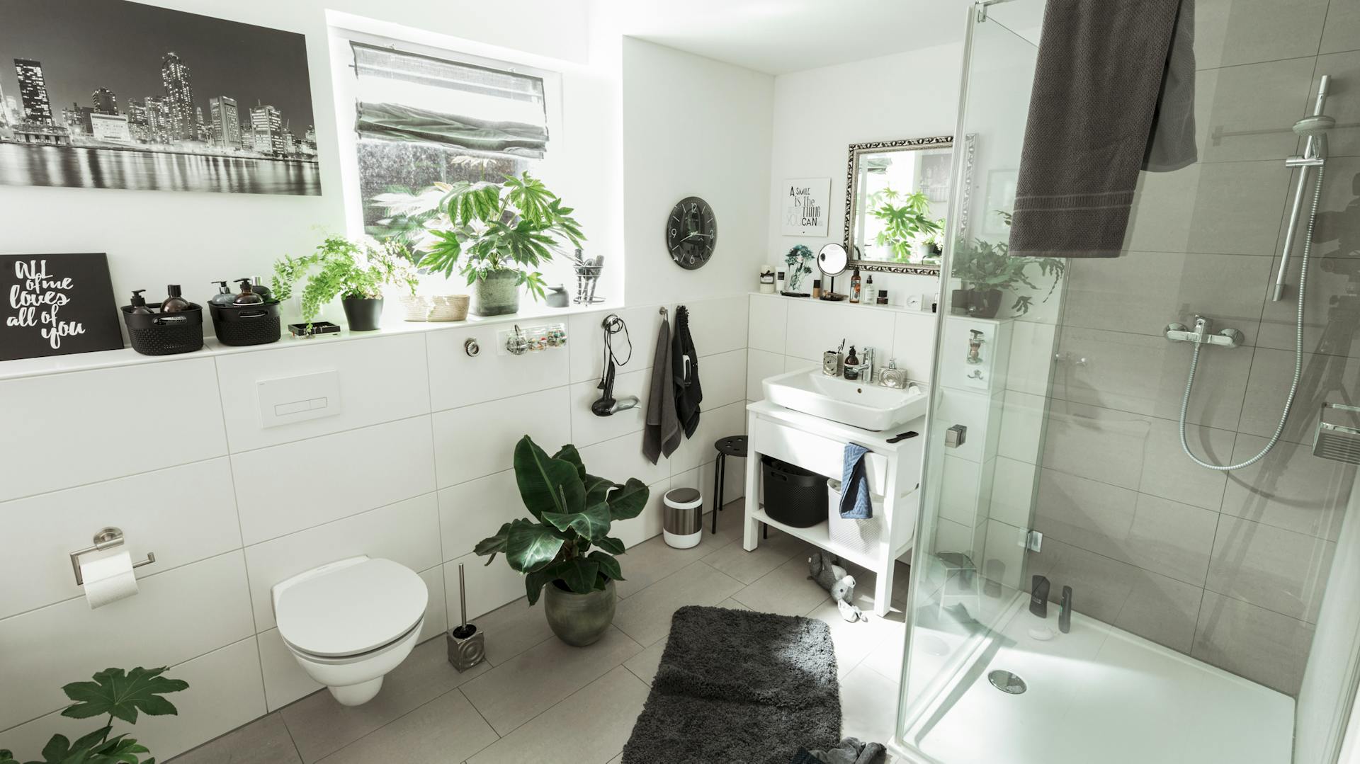 Helles Badezimmer mit Badezimmer-Pflanzen und dunklen Accessoires.