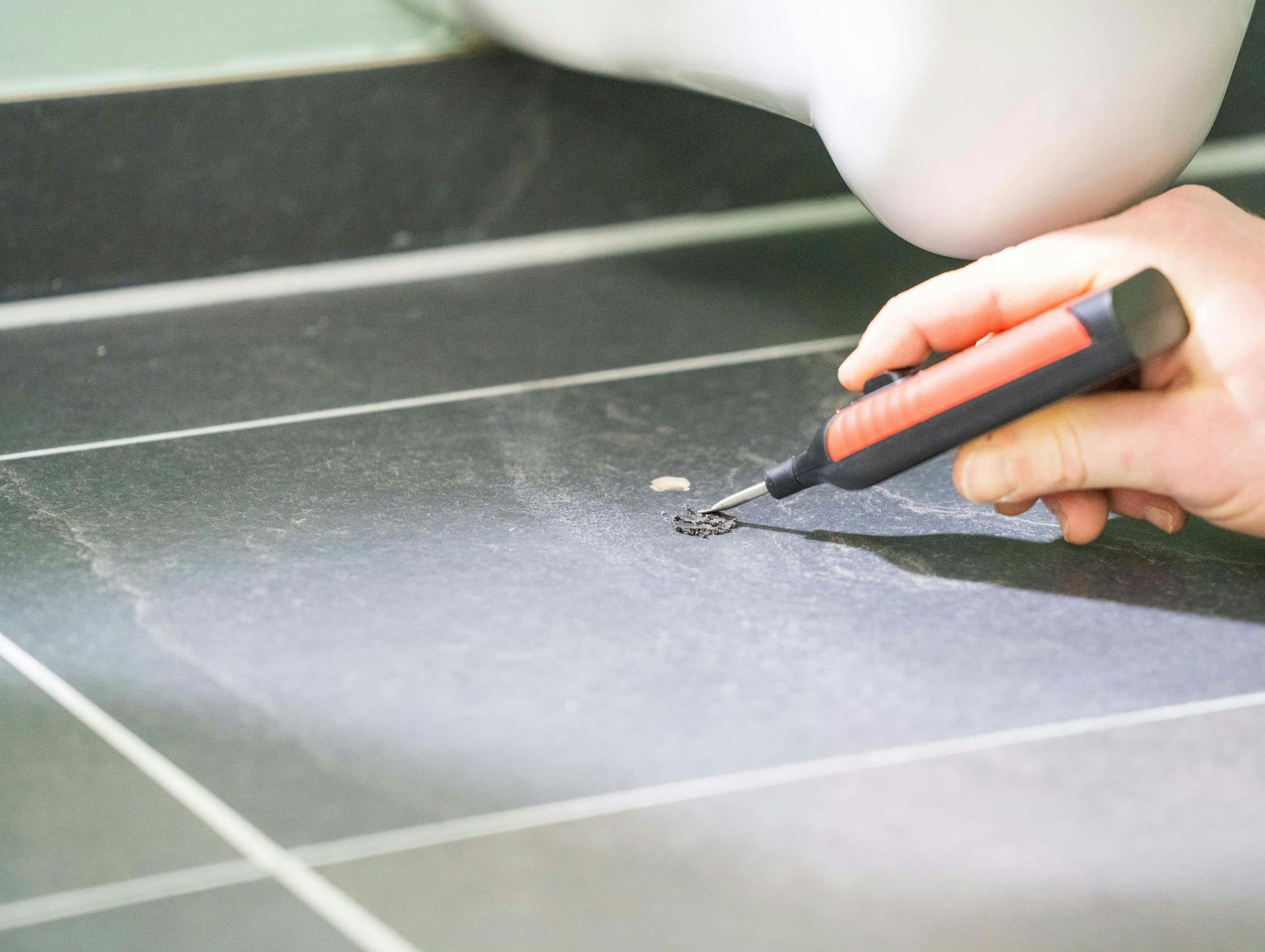 Valaki egy lyukat javít egy sötét járólapon.