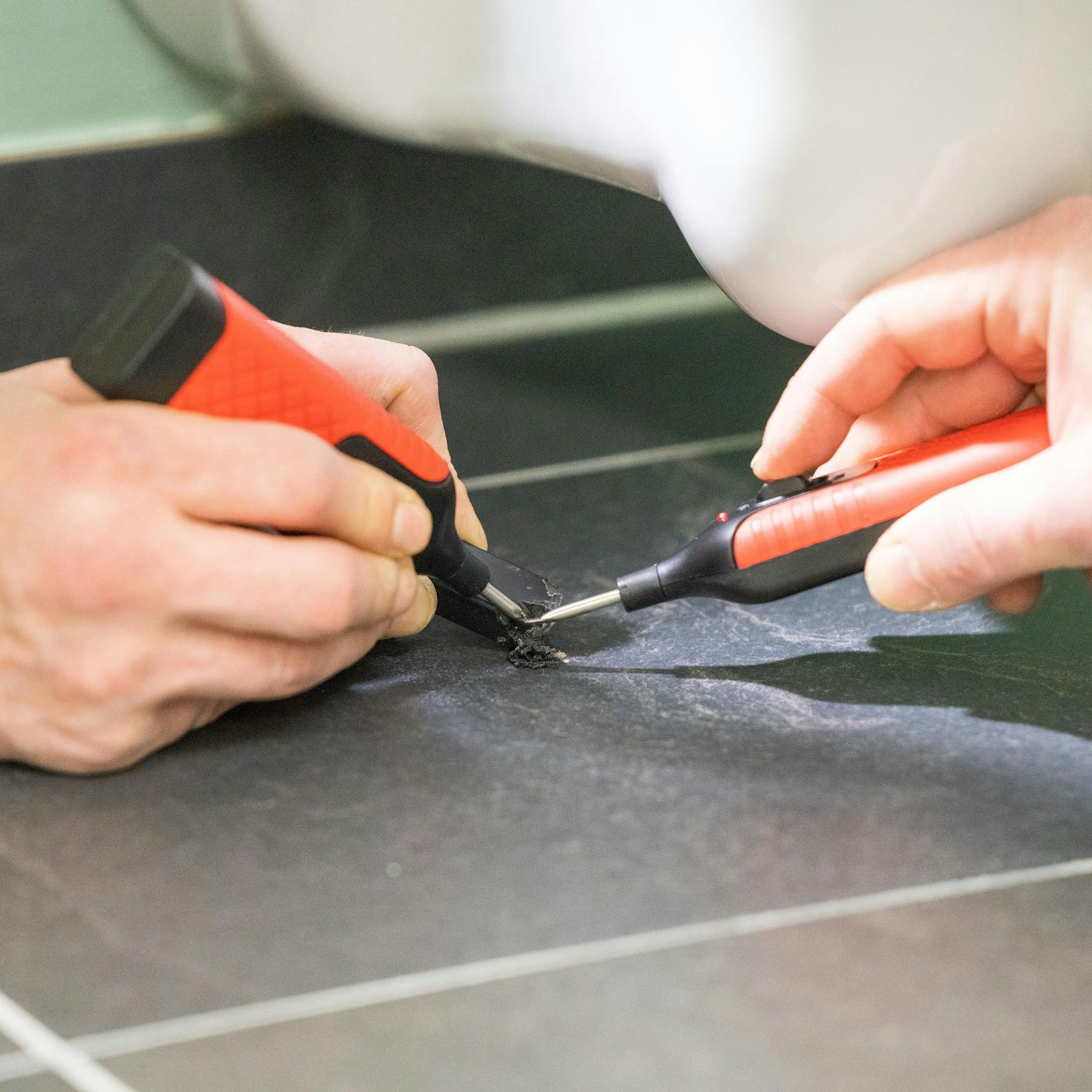 Pracovník uzatvára dieru pomocou tavného vosku zo súpravy na opravu