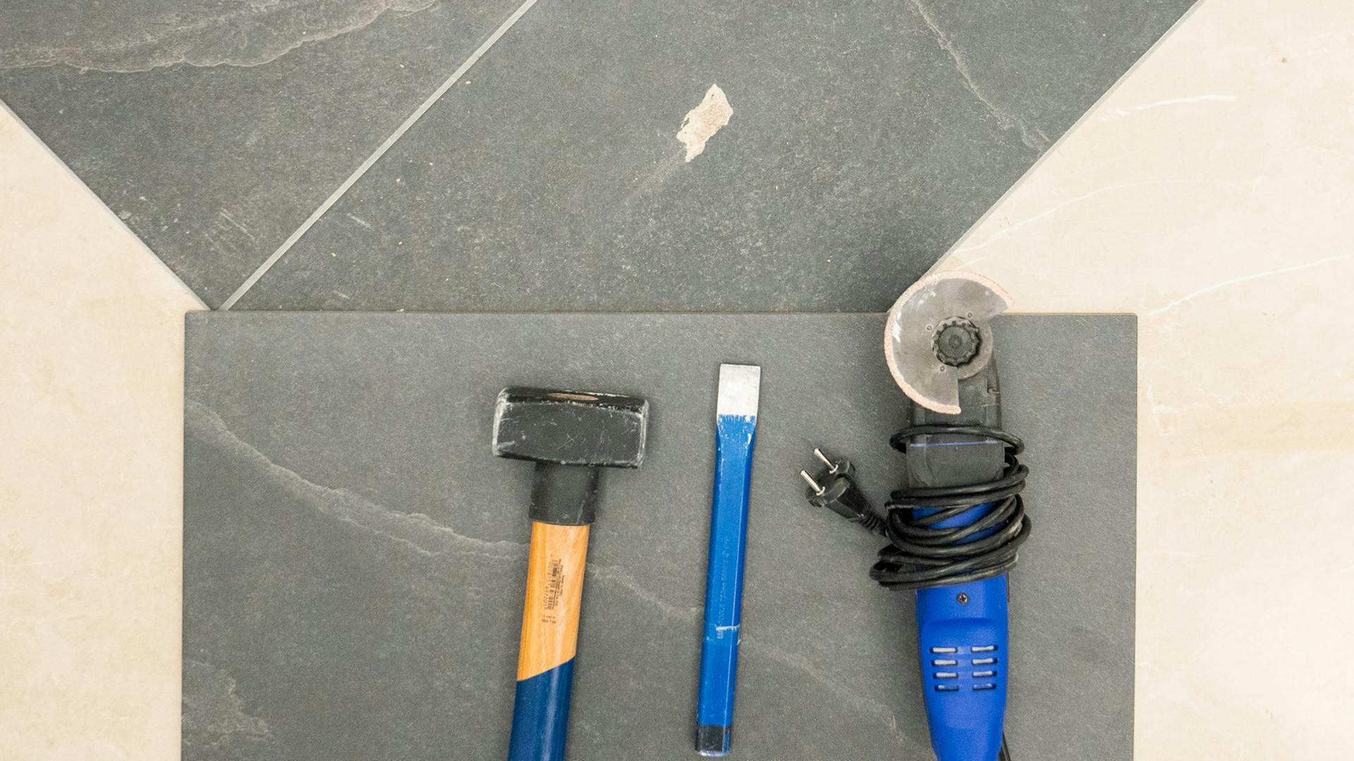 Beschädigte Fliese mit Werkzeug zum Austausch der Fliese.