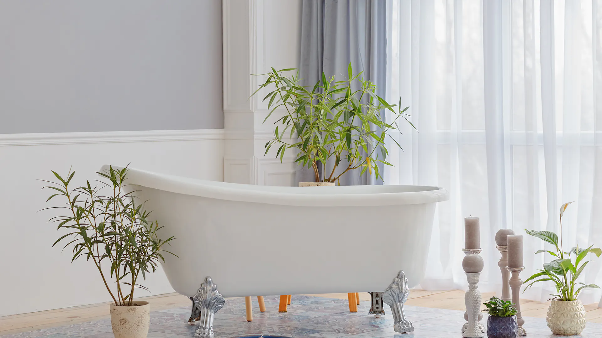 Weiße Badewanne vor hellblau tapezierter Wand von Pflanzen umgeben.