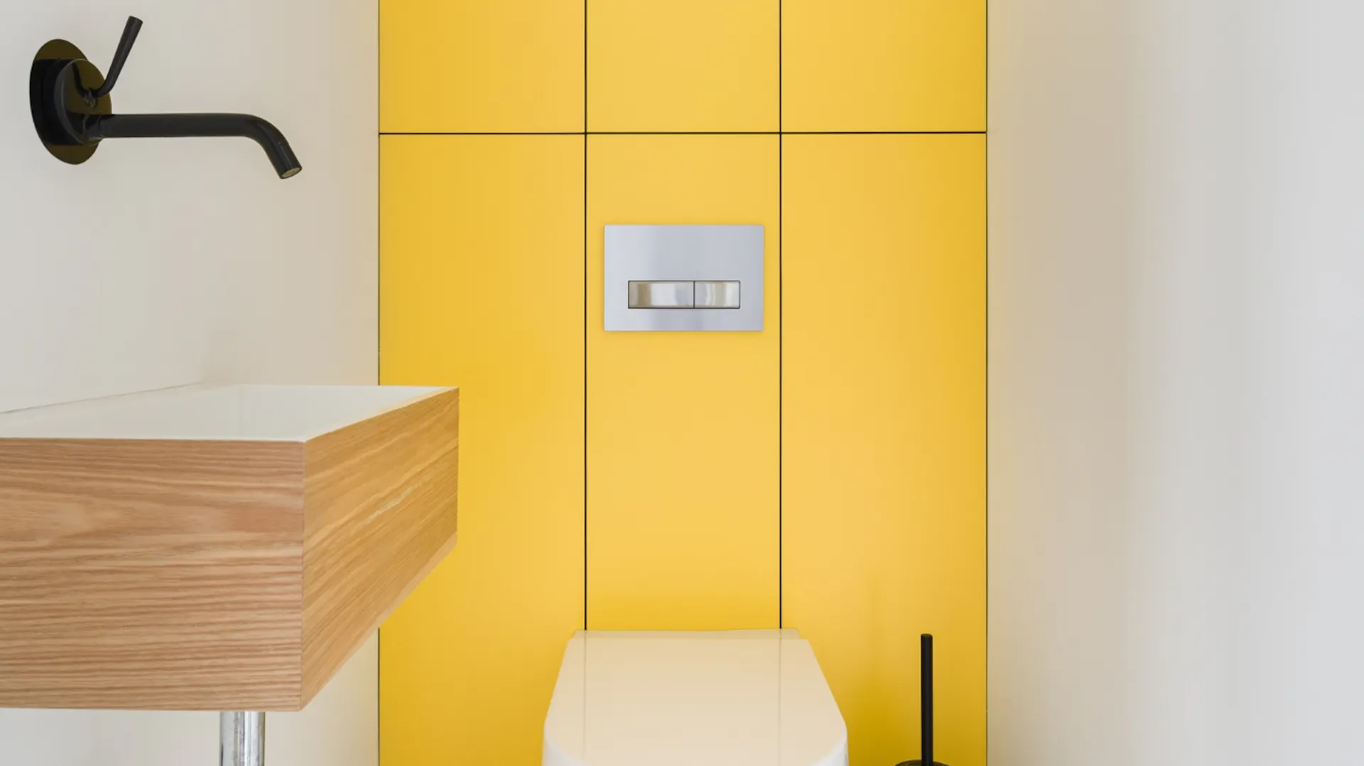 Gäste-WC in mit gelben Fliesen, davor ein weißes WC. Seitlich ein kleines Waschbecken