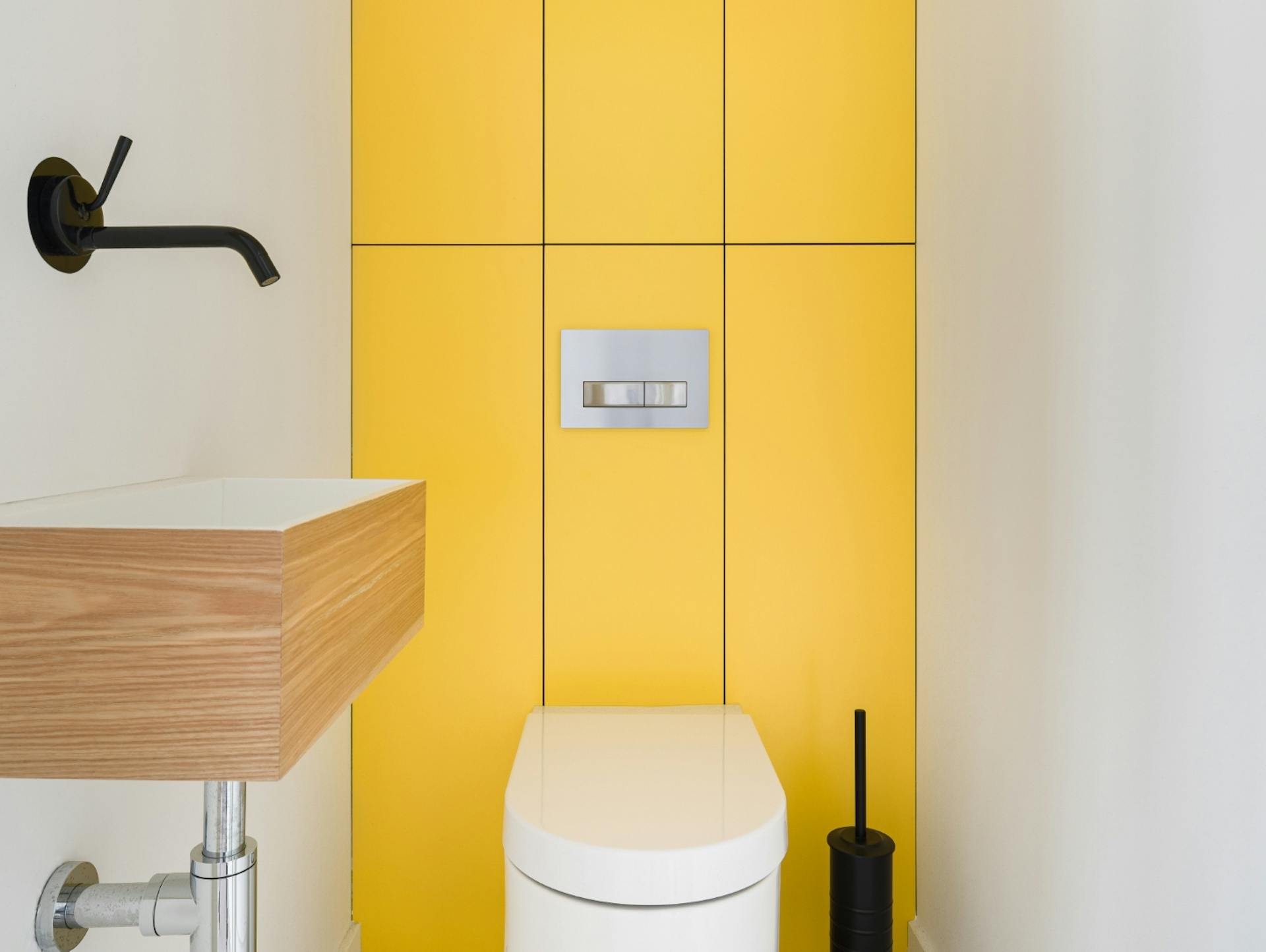 Gäste-WC in mit gelben Fliesen, davor ein weißes WC. Seitlich ein kleines Waschbecken