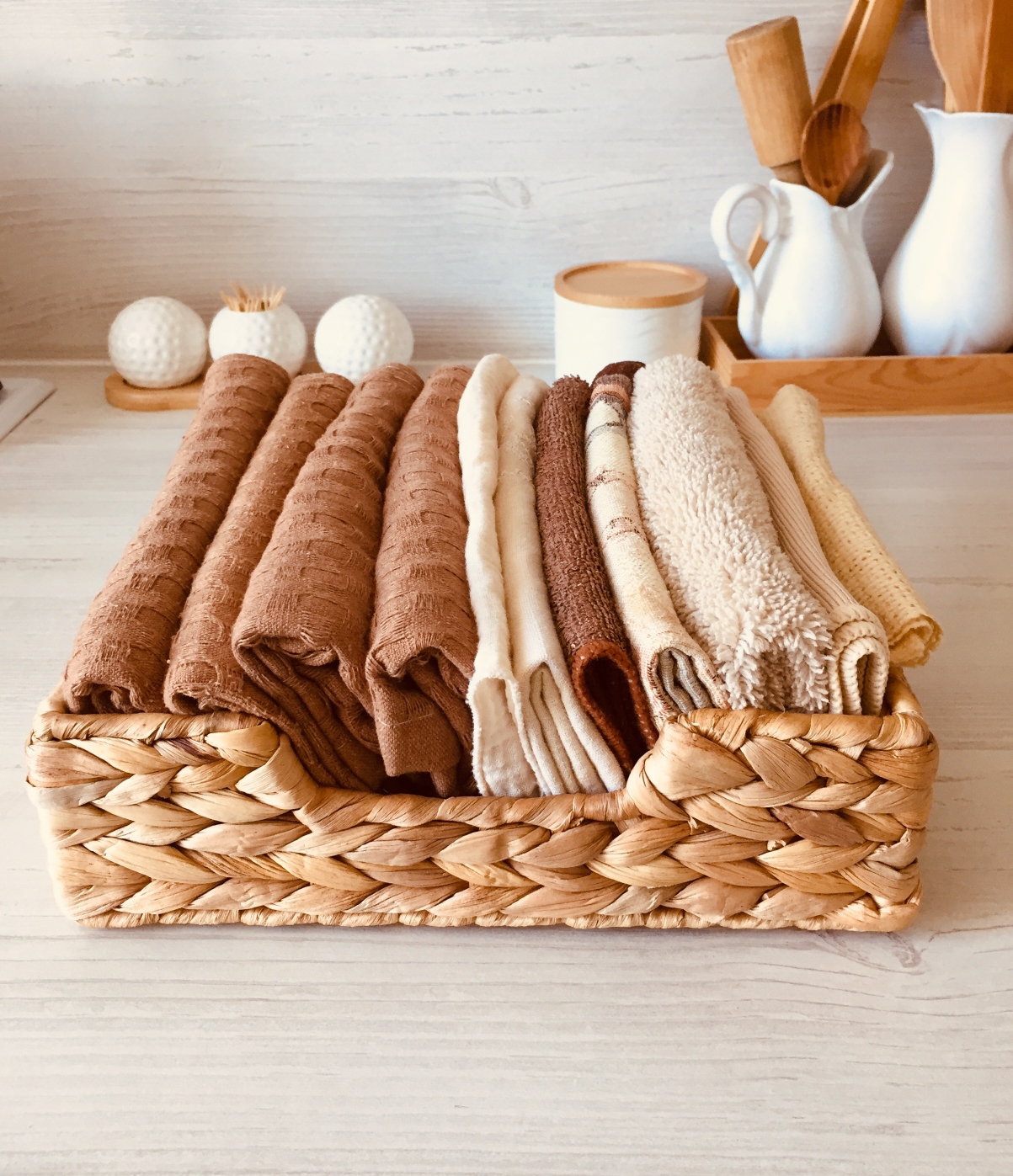 Prútený košík s hnedými a béžovými uterákmi.