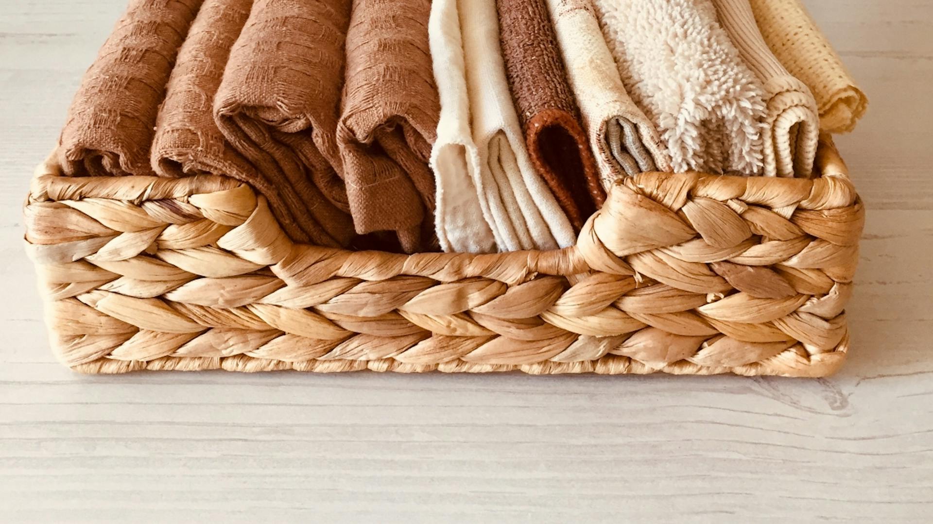 Weidenkorb mit braunen und beigefarbenen Handtüchern.