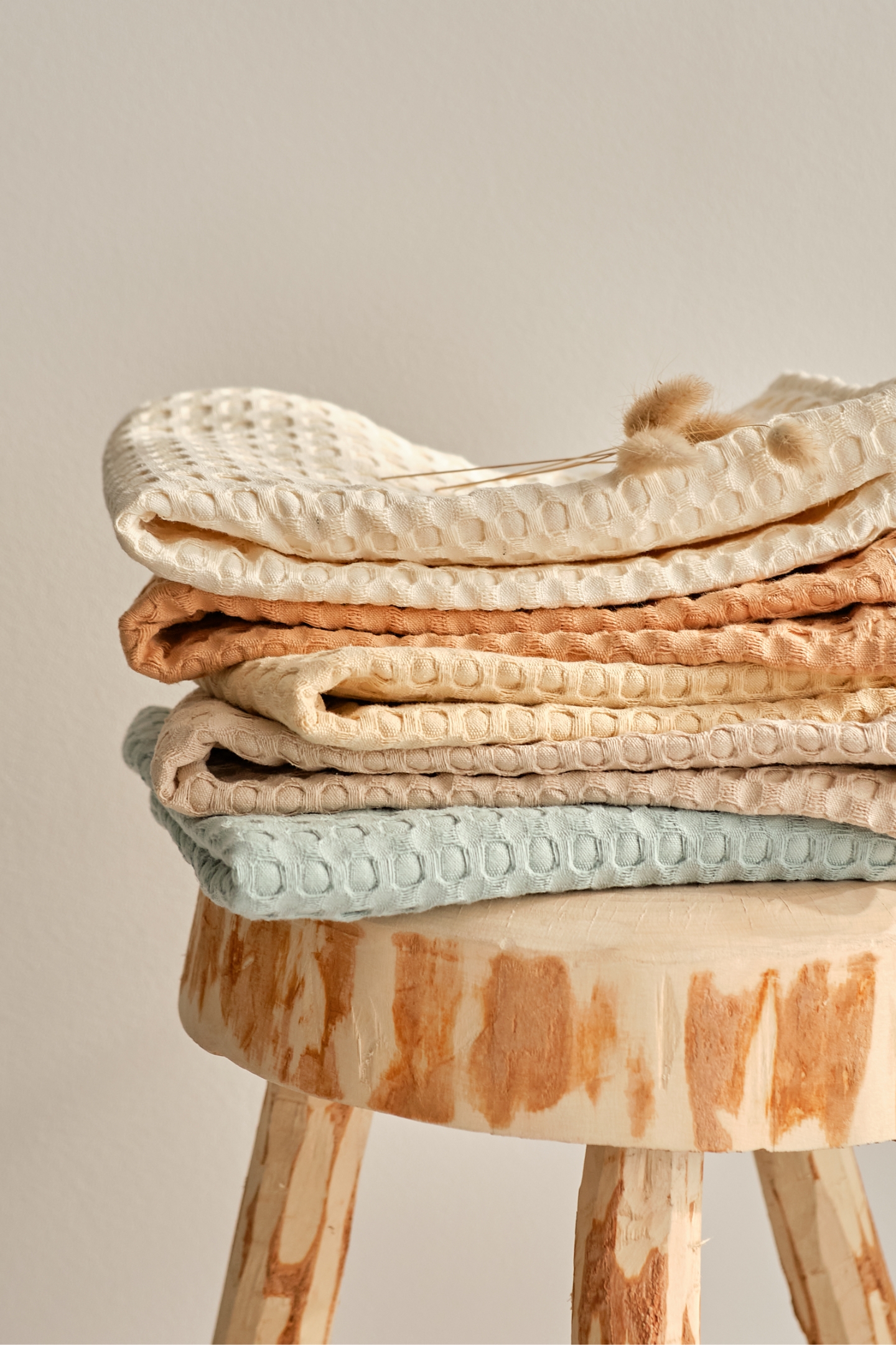 Holzhocker mit pastellfarbenen Handtüchern.