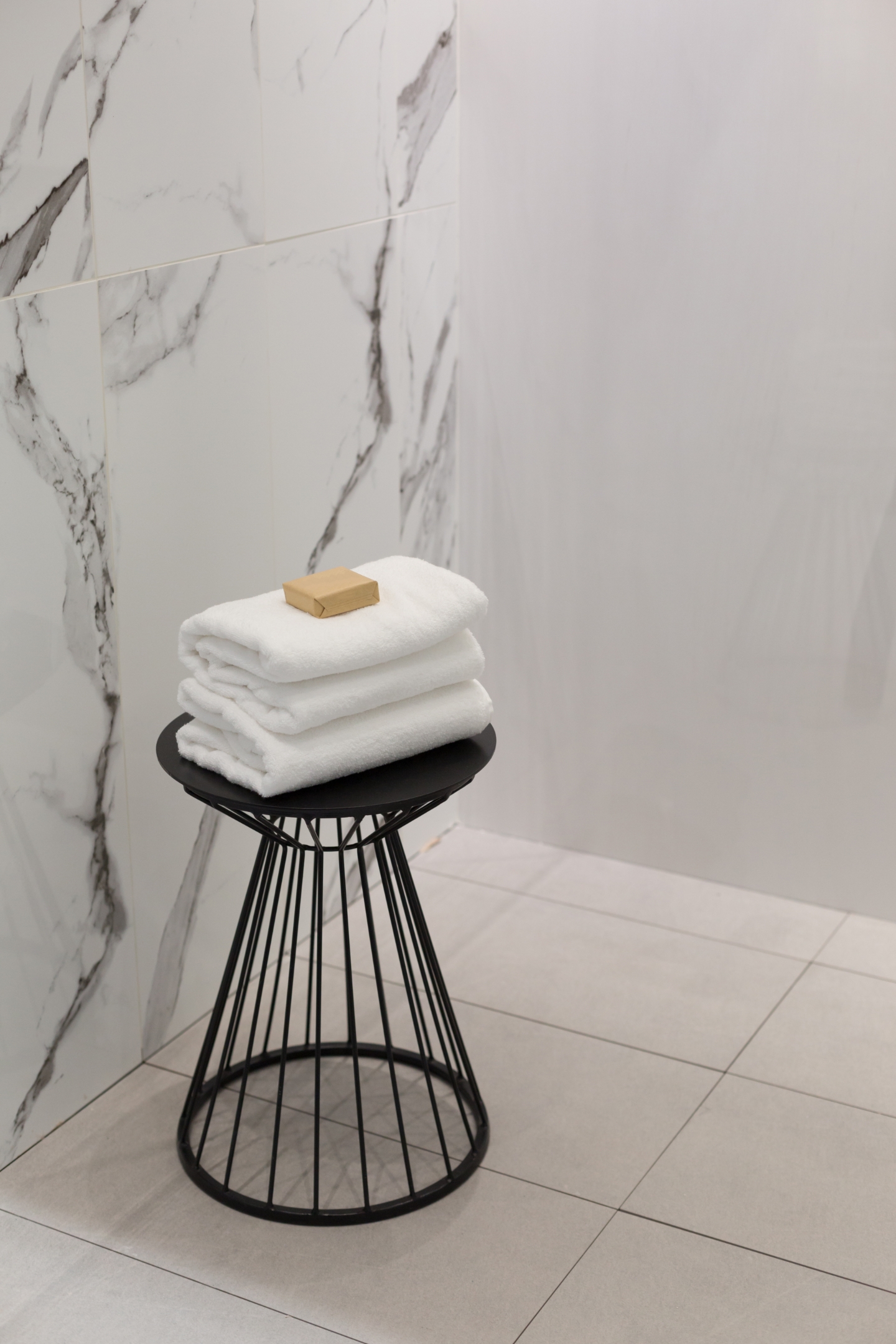 Schwarzer Metallhocker, auf dem weiße gefaltete Handtücher liegen.