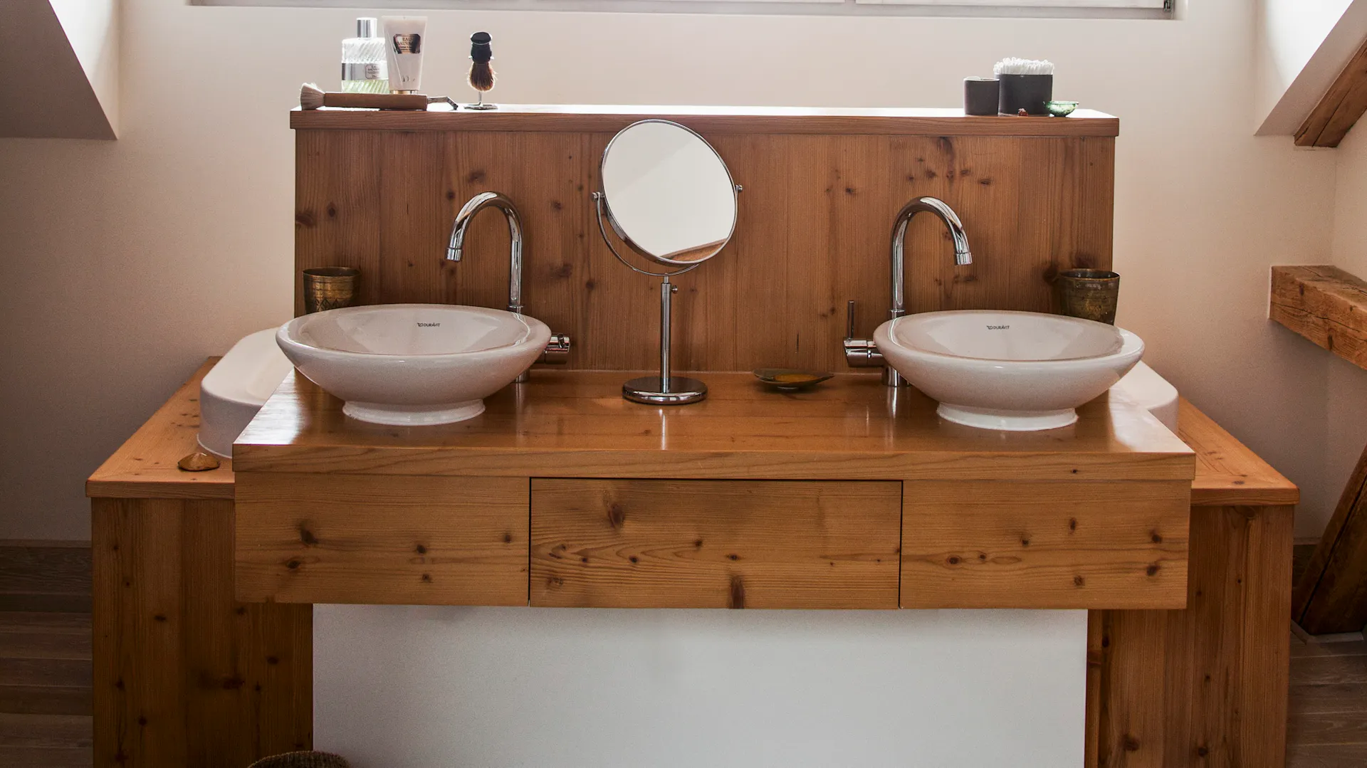 Ein Badezimmer mit Holzwaschtisch und Holzbalken an der Decke sowie Holzboden.