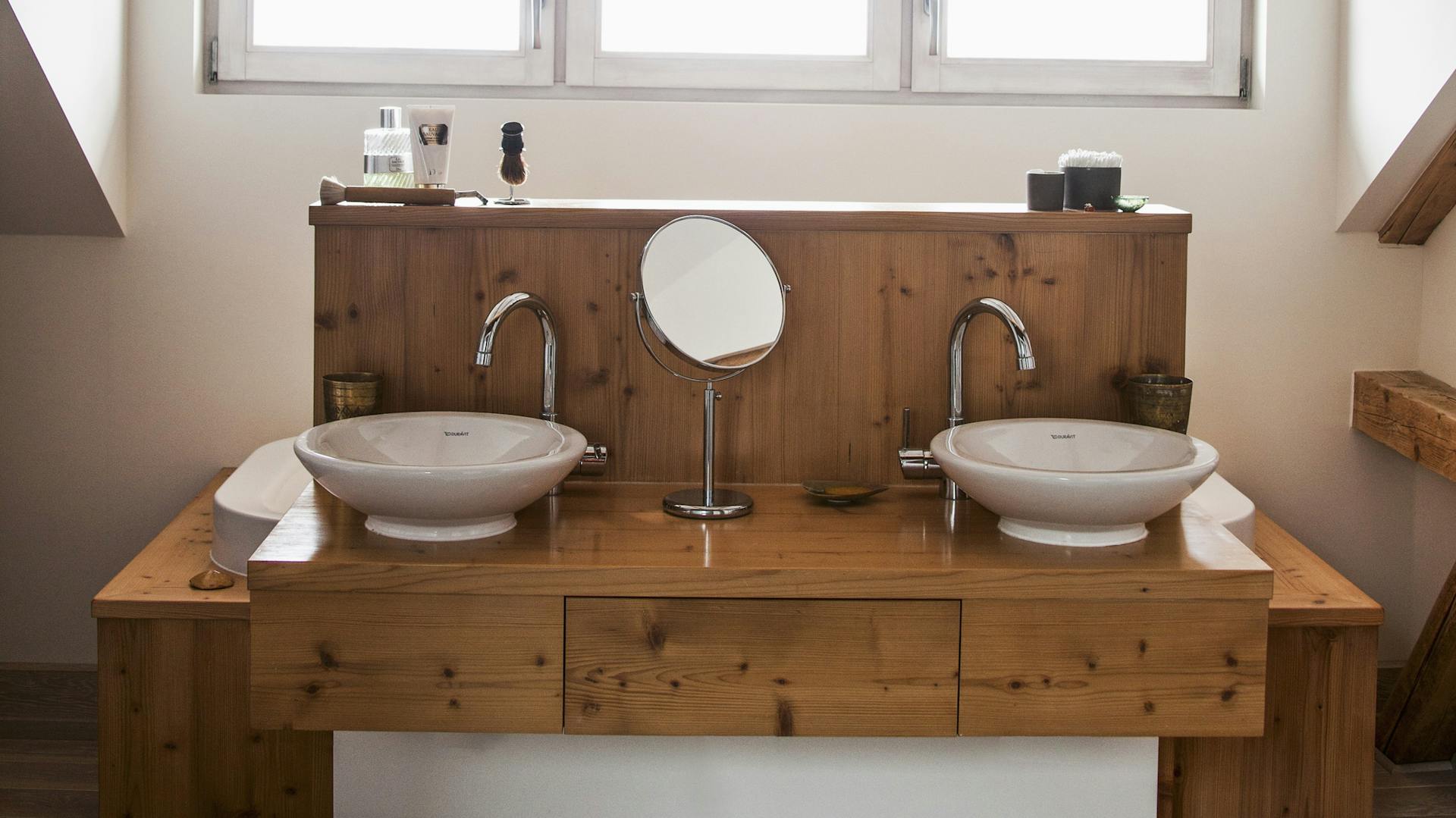 Weiße runde Badewanne. Darauf liegt ein Holzbrett mit Handtüchern und Seifen.