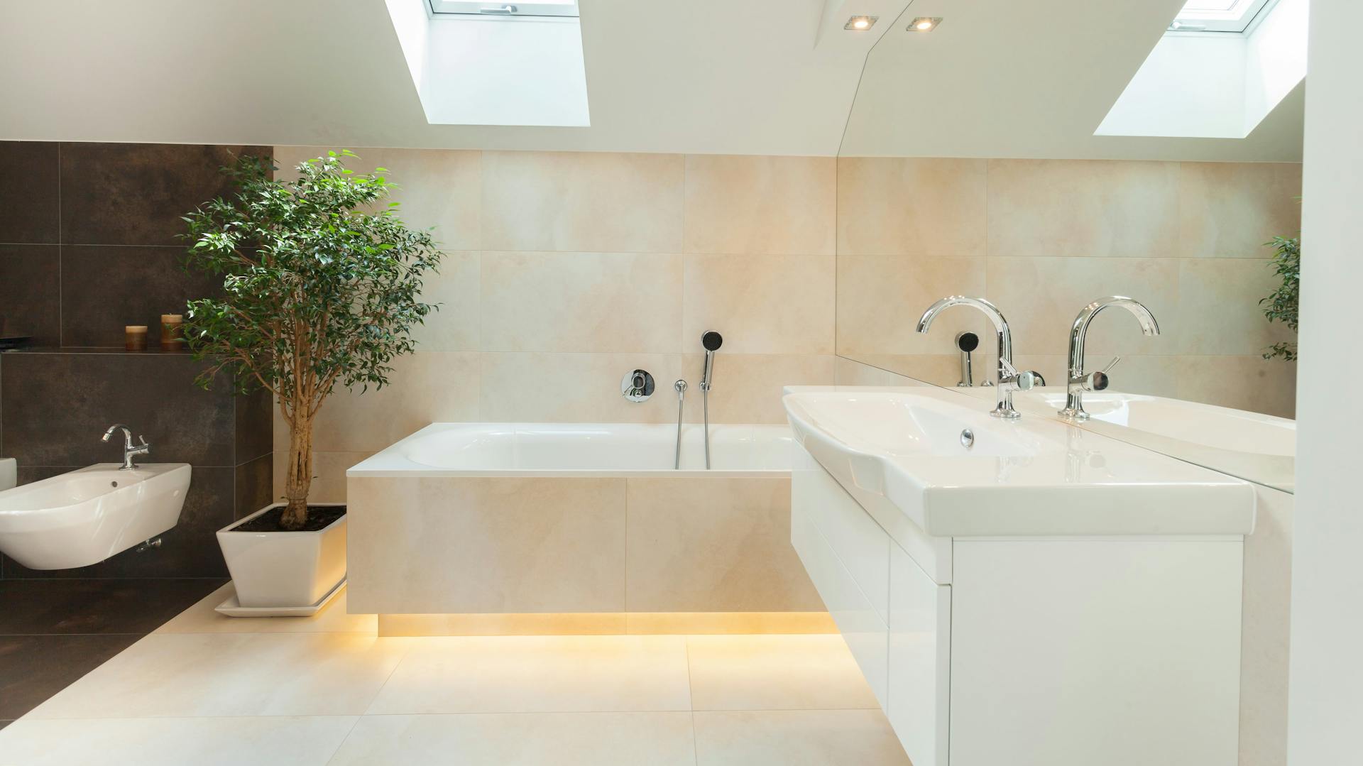 Bagno color crema con lavello, bidet e vasca da bagno con illuminazione indiretta.