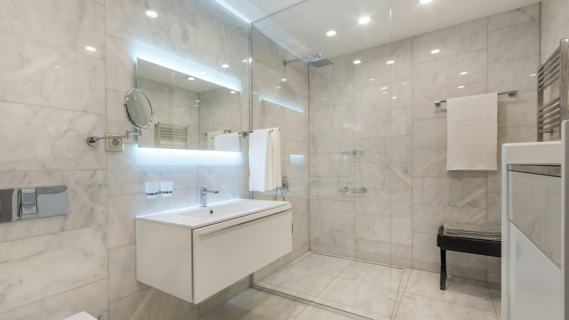 Bagno luminoso con illuminazione indiretta sullo specchio, sul soffitto e sulla parete.