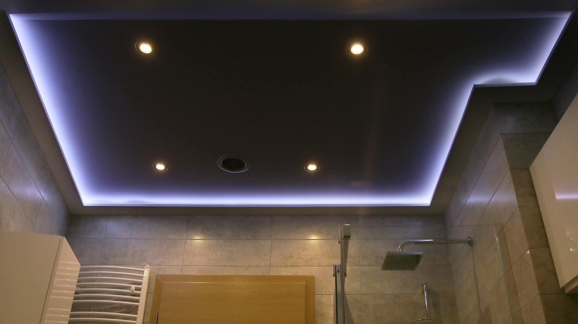 Bagno con strisce LED e proiettori da incasso sul soffitto