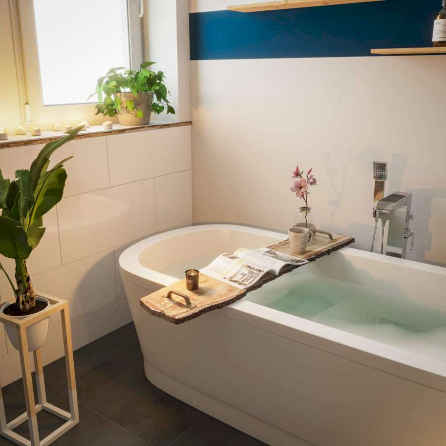 Eine Badewannenablage mit Baumkante, auf der sich eine Zeitung, eine Tasse, eine Orchidee und eine Kerze befinden
