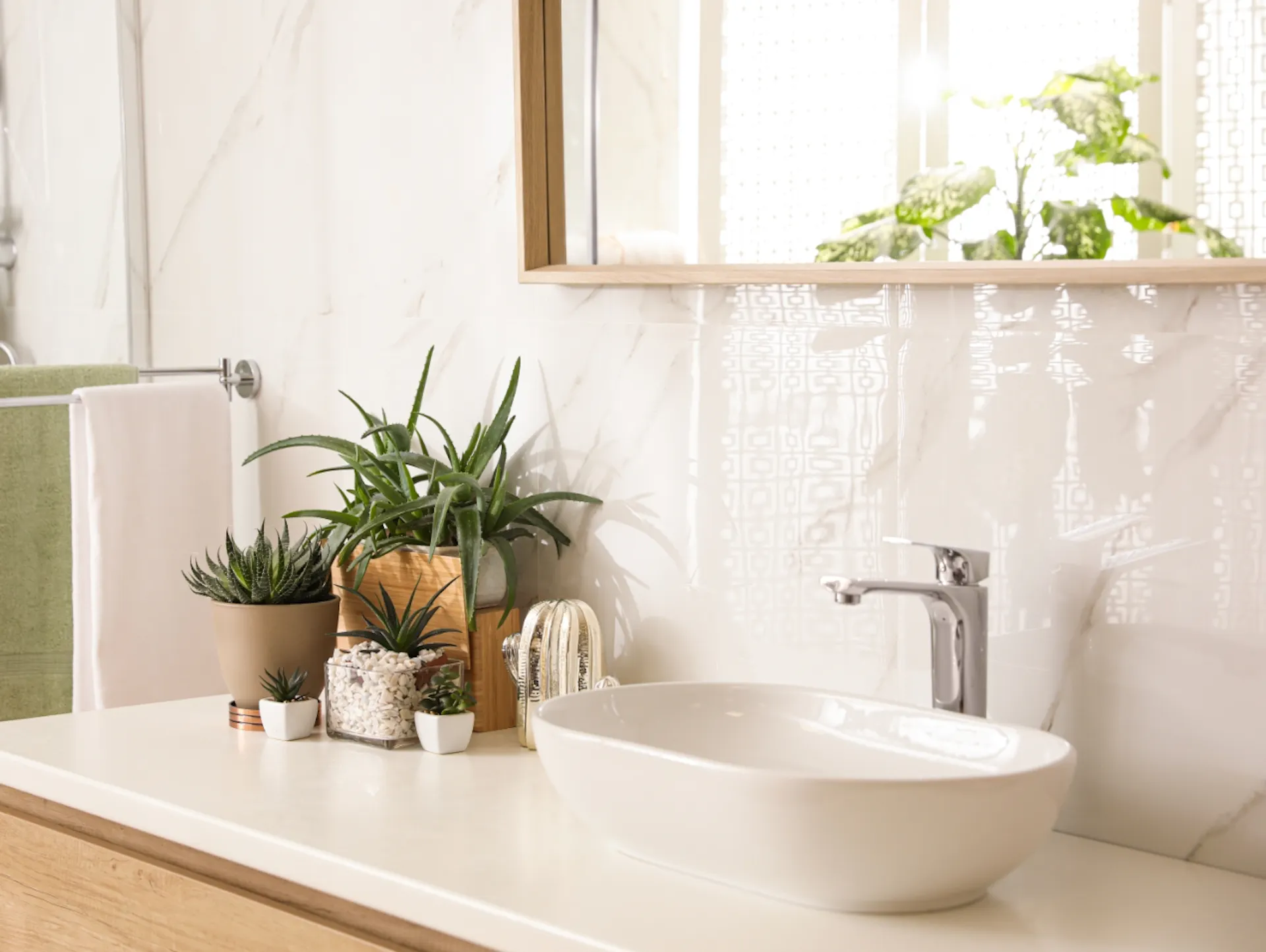 Piastrelle bianche davanti a un mobile lavabo in legno con lavabo bianco e piante.