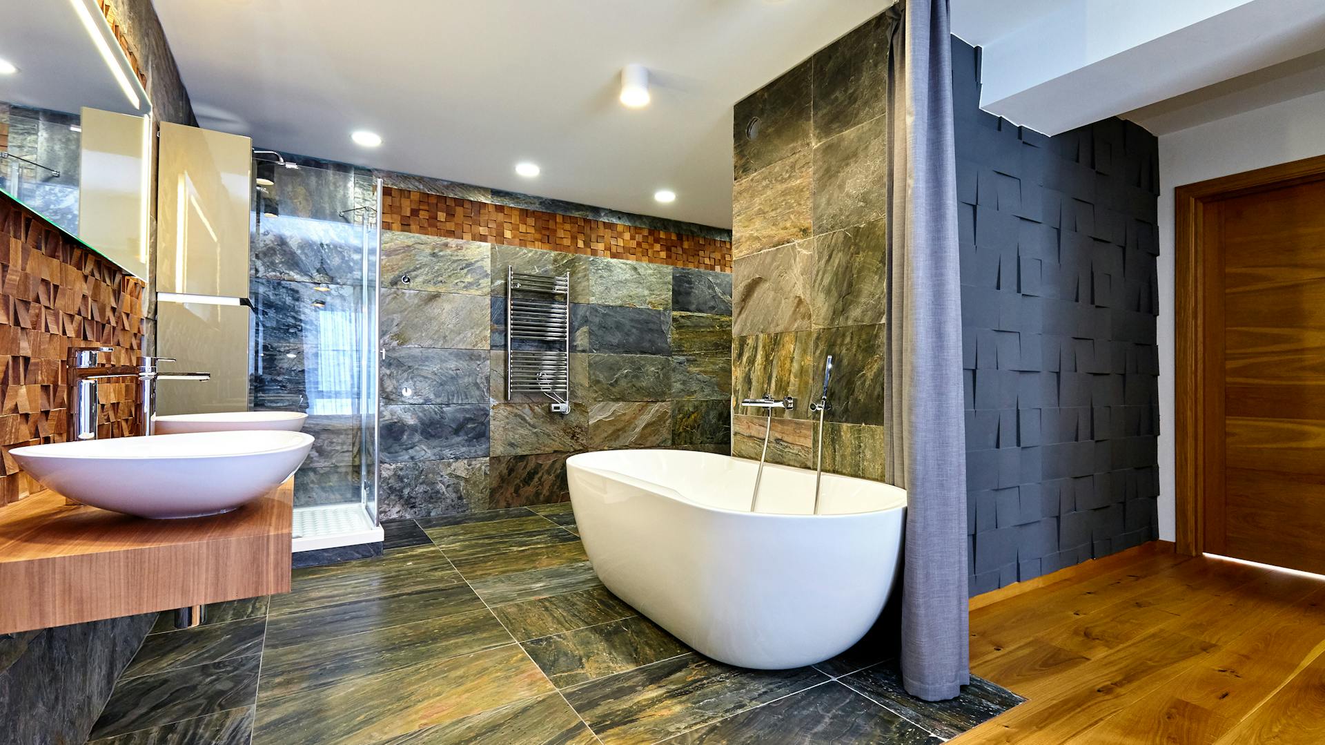 Kúpeľňa s tmavosivým obkladom v mramorovom vzhľade na stene a podlahe.