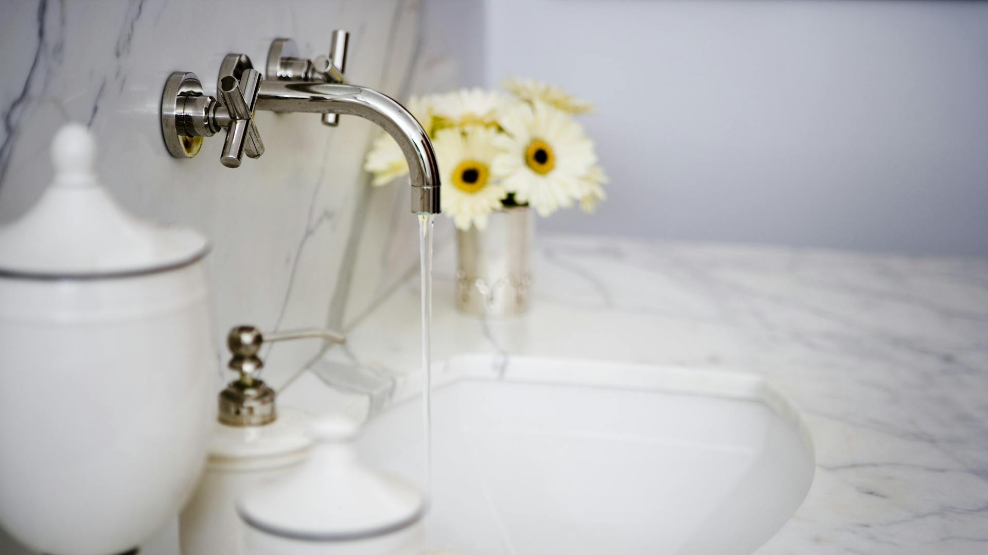 Mramorové umývadlo kombinované s kvetmi a kovovou batériou.