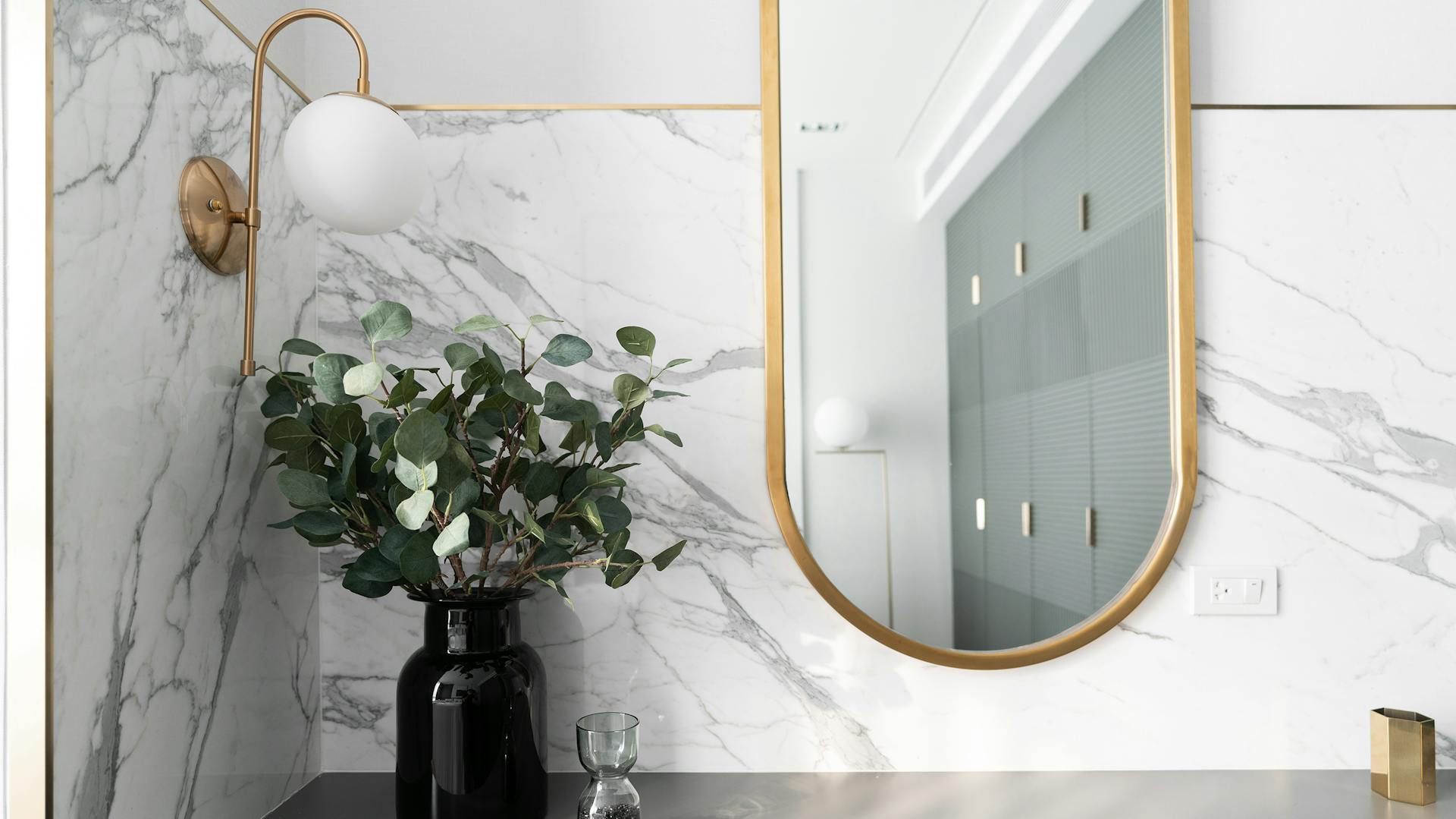 Kúpeľňa s obkladom v mramorovom vzhľade a zlatými zrkadlami.