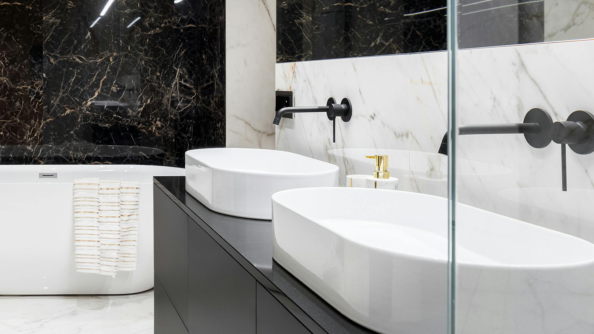 Kúpeľňa s čiernym mramorom a čiernymi batériami.